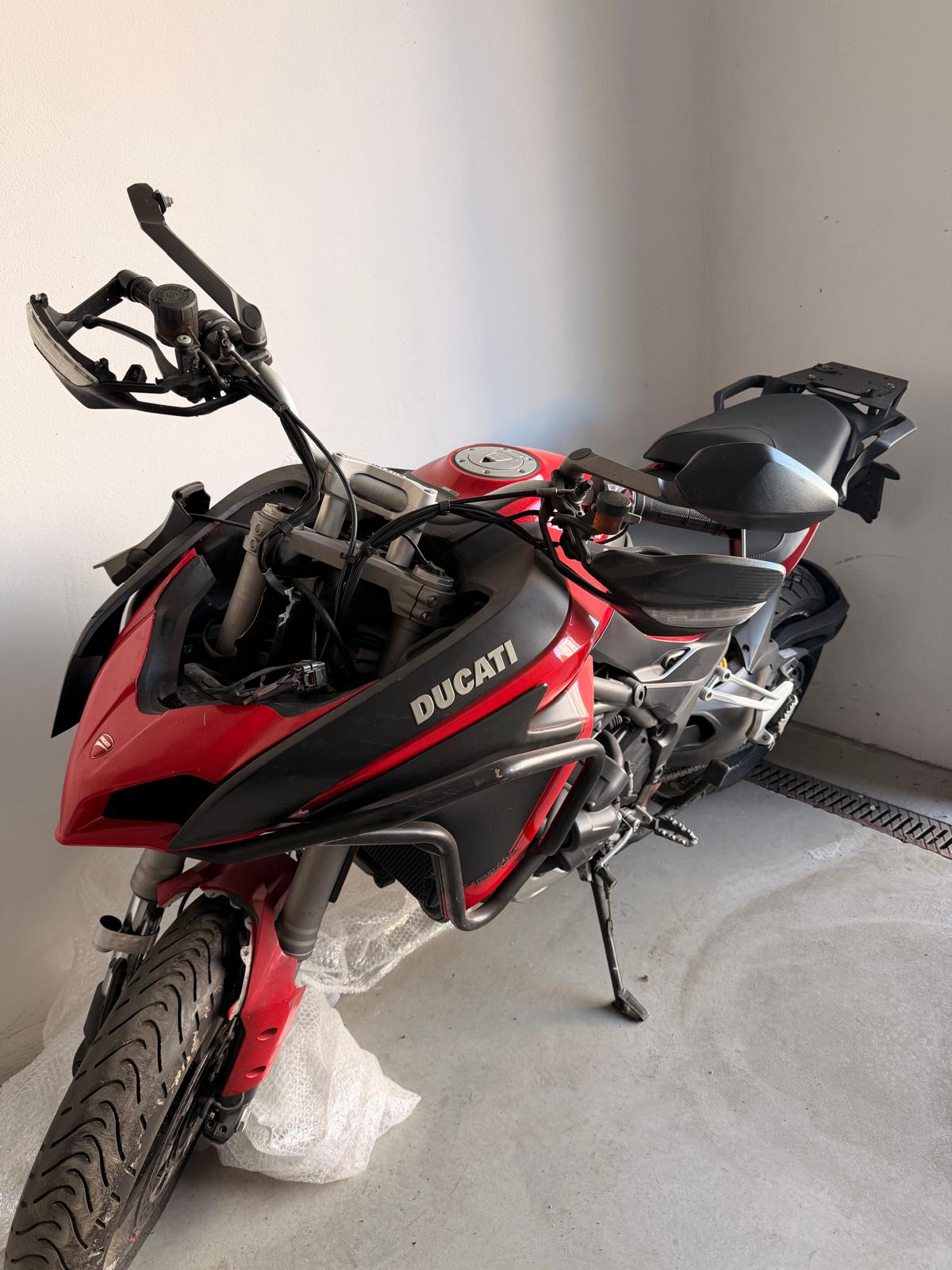Przód czerwonego Ducati Multistrada. Częściowo rozebrany przód z widocznym brakiem licznika. Motocykl stojący na bocznej stopce.