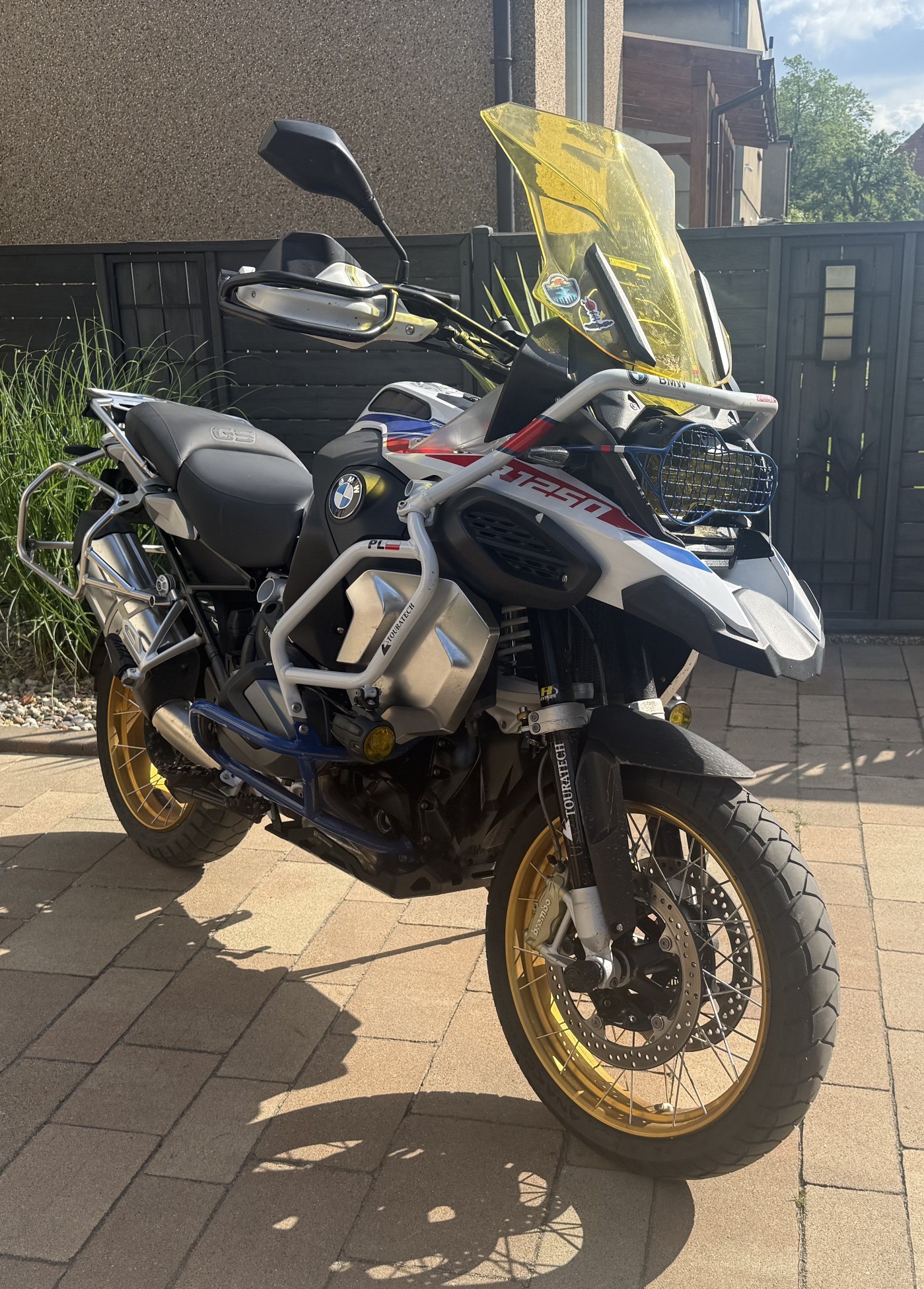 Motocykl turystyczny BMW R 1250 GS Adventure w biało-niebiesko-czerwonym malowaniu, wyposażony w liczne akcesoria off-road.