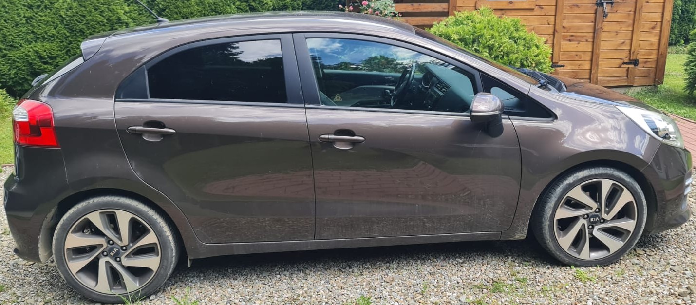 Brązowy Kia Rio, widok z boku, z widocznymi detalami nadwozia i felg.