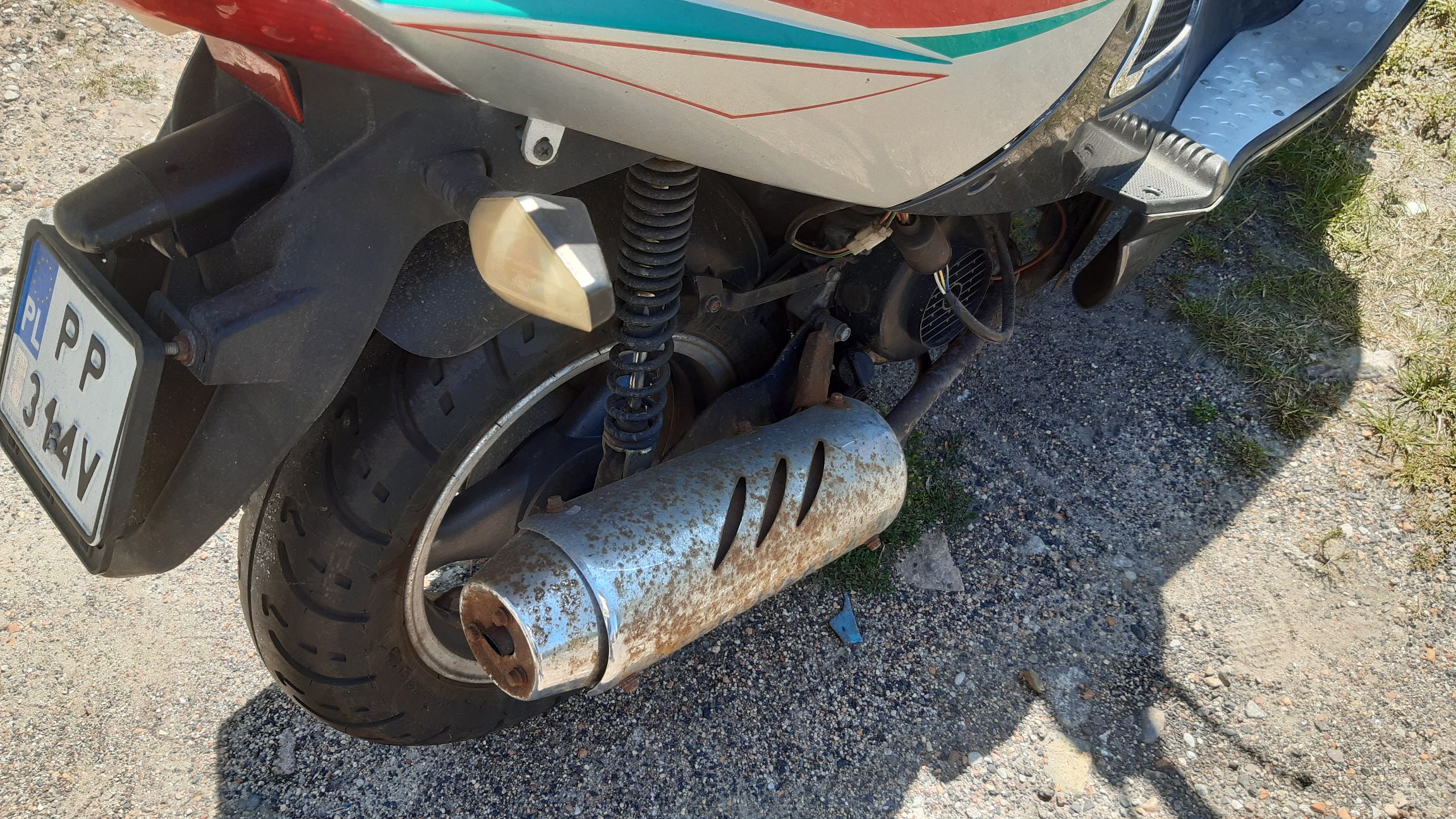 Tylne koło motoroweru, skorodowany wydech