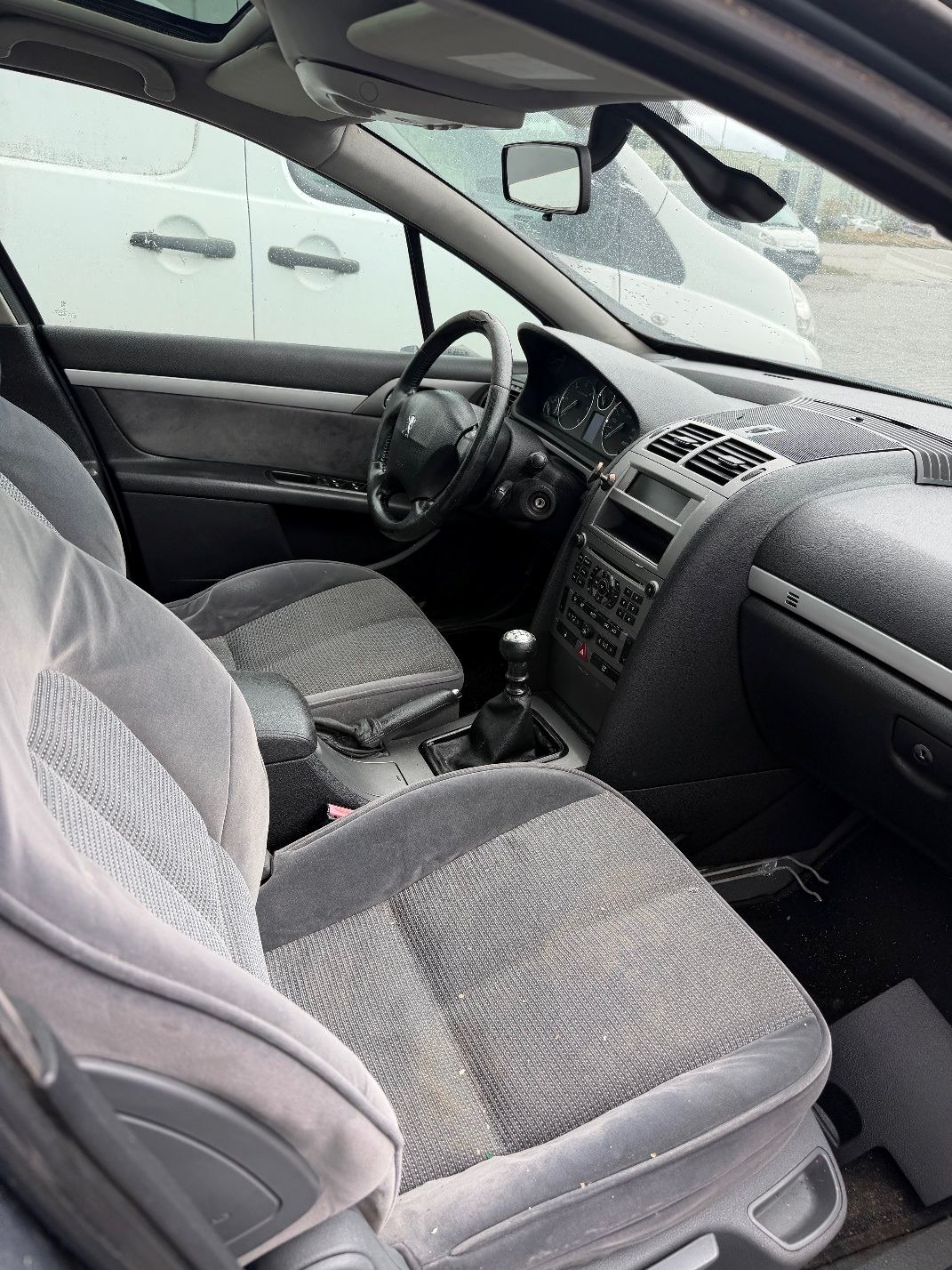 Szary Peugeot 407 SW, szary fotel kierowcy i pasażera z wyraźnymi śladami eksloatacji i zabrudzeniami, niekompletna konsola.