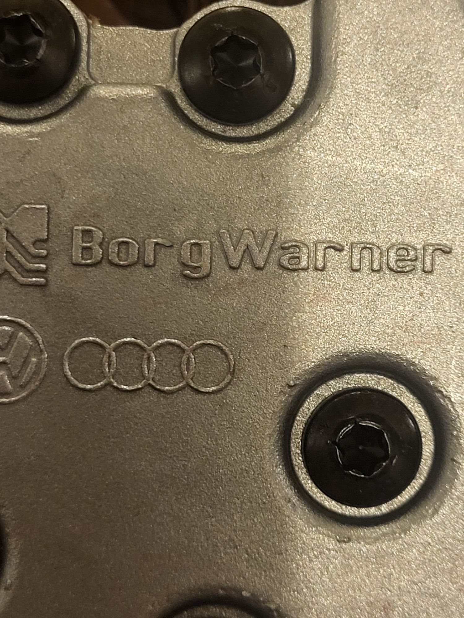  część samochodowej skrzyni biegów z wytłoczonym napisem „Borg Warner” oraz logo marek Audi