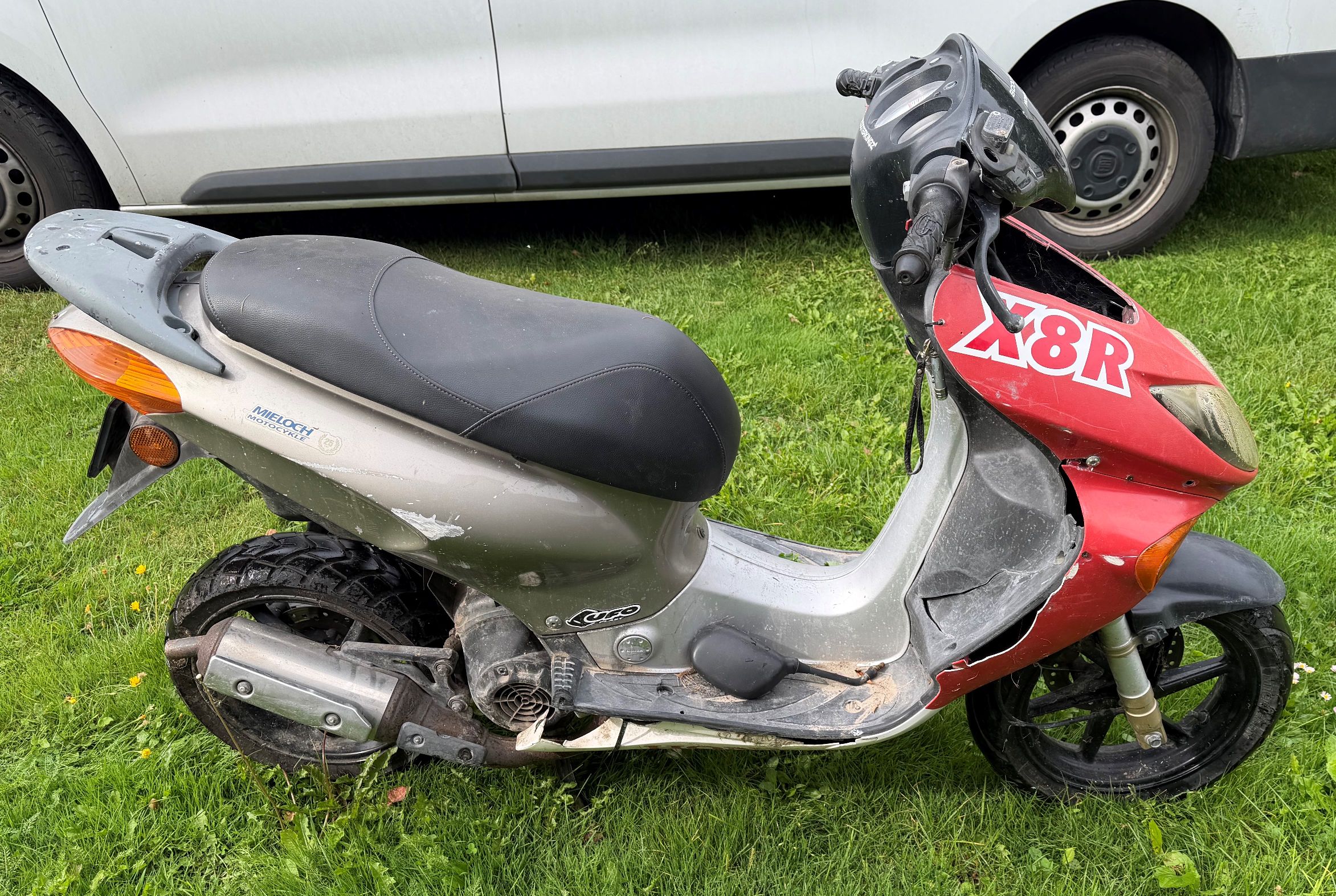 Skuter w kolorze czerwono srebrnym. Widok z prawej strony motoroweru.