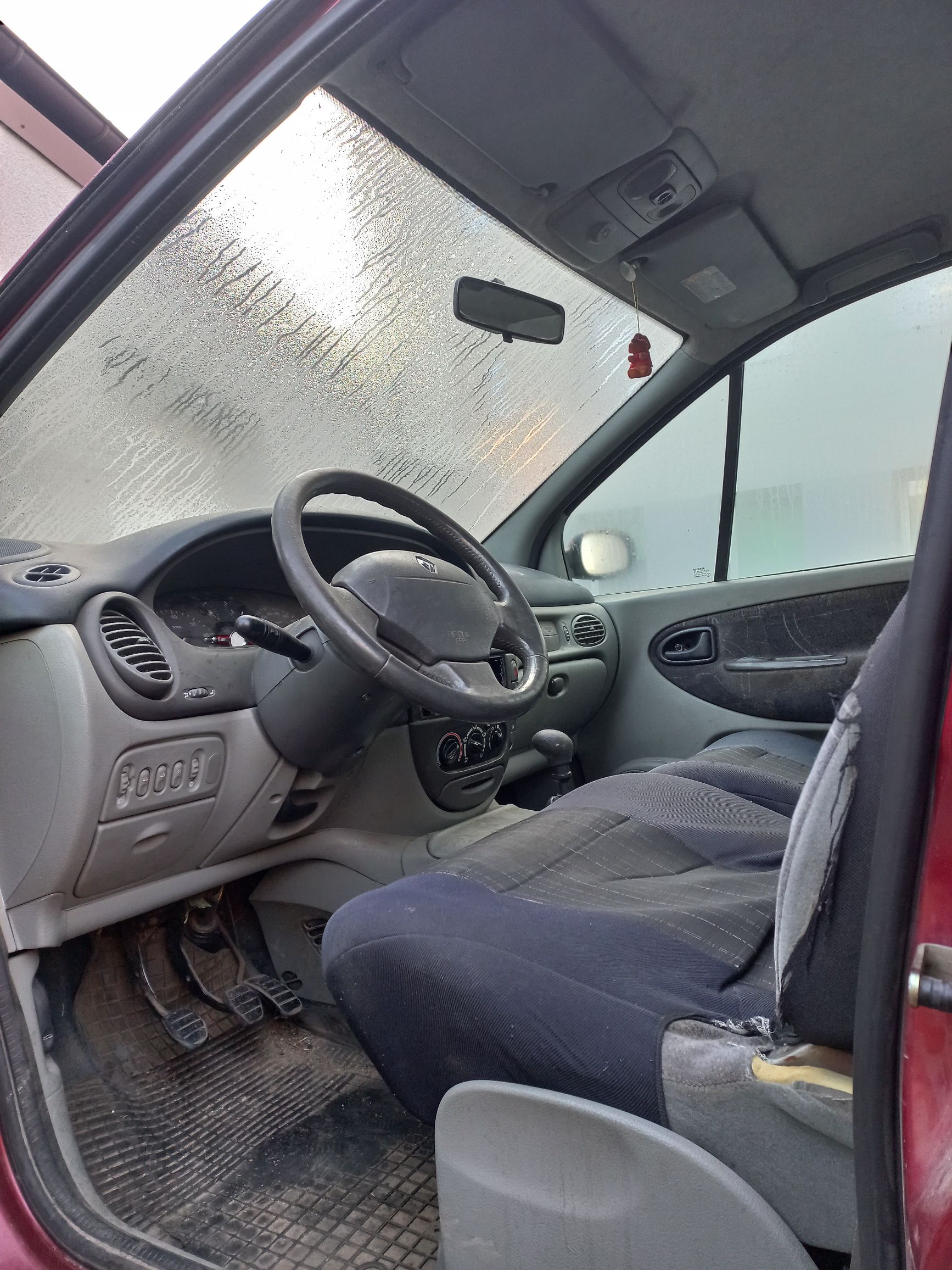 Wnętrze starego samochodu Renault z szarą deską rozdzielczą, ciemnymi fotelami i zaparowaną przednią szybą rano.