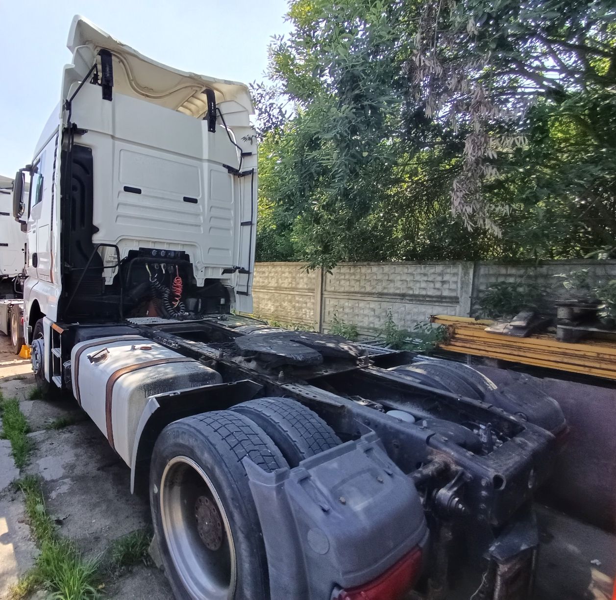 Biały ciągnik siodłowy widziany z tyłu kabiny, z odsłoniętym podwoziem.