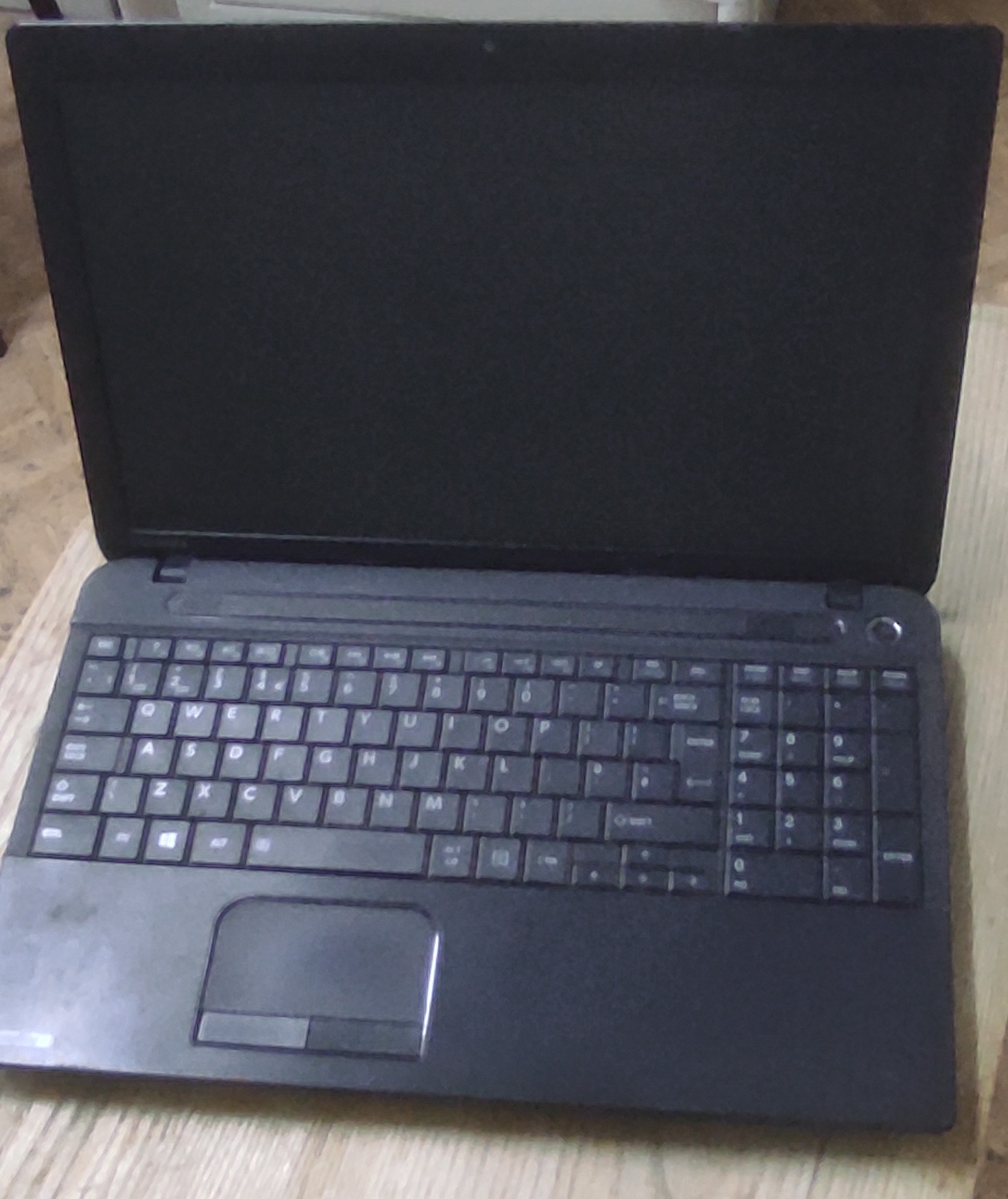 Otwarty laptop Toshiba Satellite z widoczną klawiaturą i ekranem.