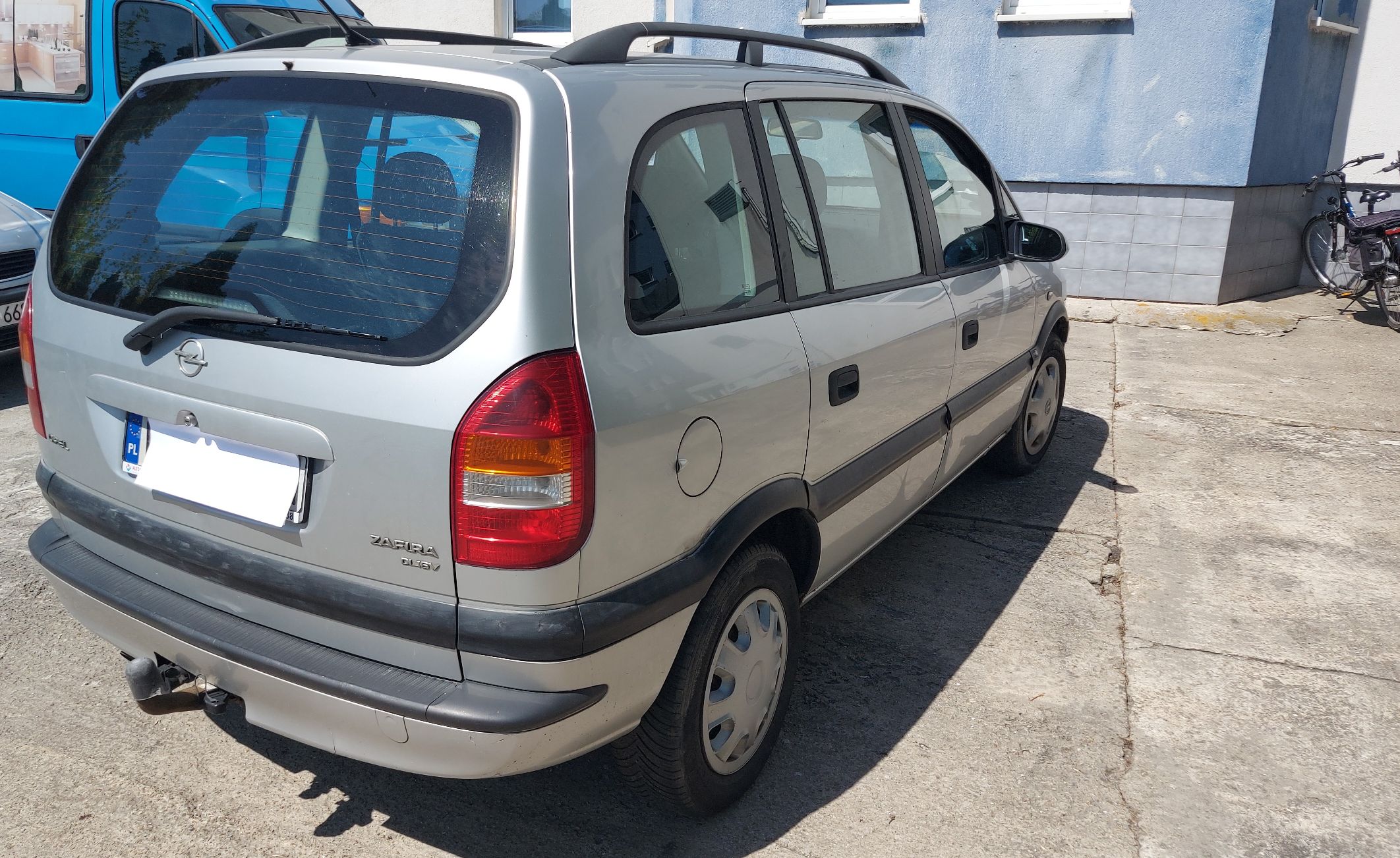 Opel Zafira A widok od tyłu z prawej perspektywy. Samochód posiada czarne listwy ochronne, relingi dachowe oraz hak holowniczy.