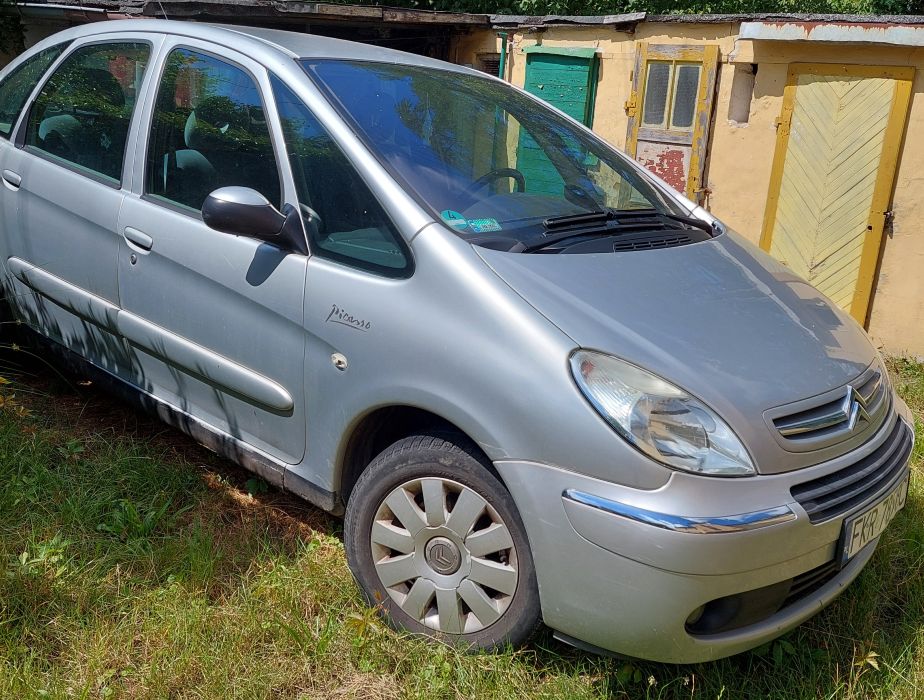 Przód i prawy bok srebrnego Citroena Xsara Picasso, widoczne otarcia zderzaka, ślady korozji na progu