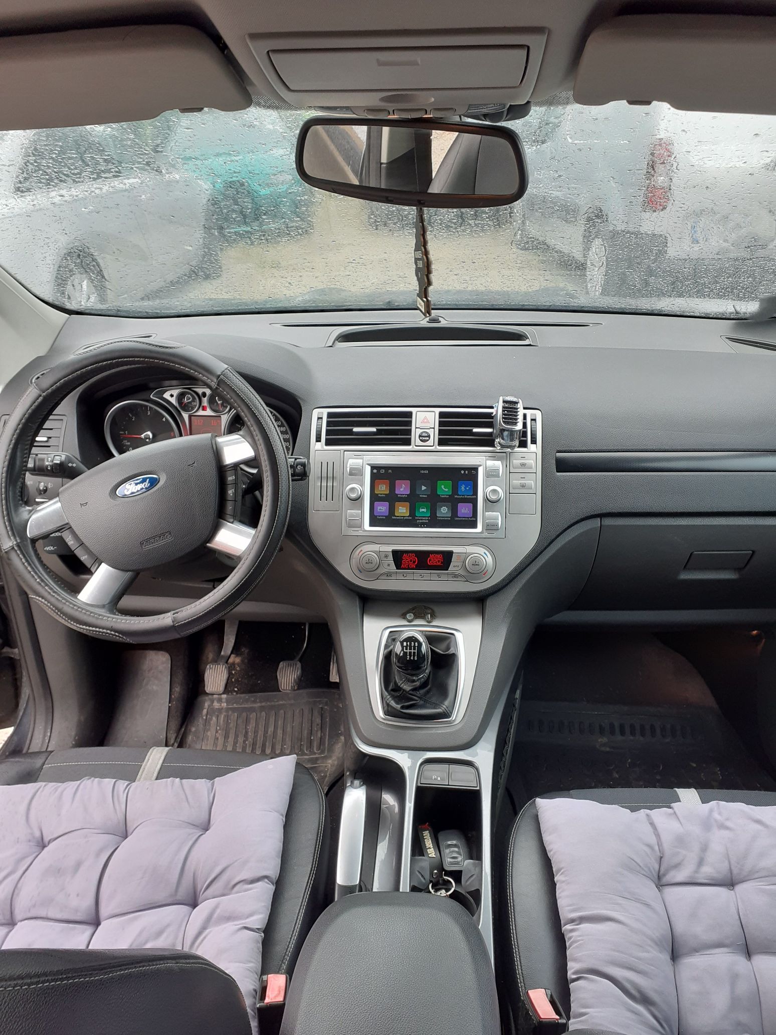 Wnętrze Forda Kuga z czarną deską rozdzielczą, dotykowym ekranem, manualną skrzynią biegów.