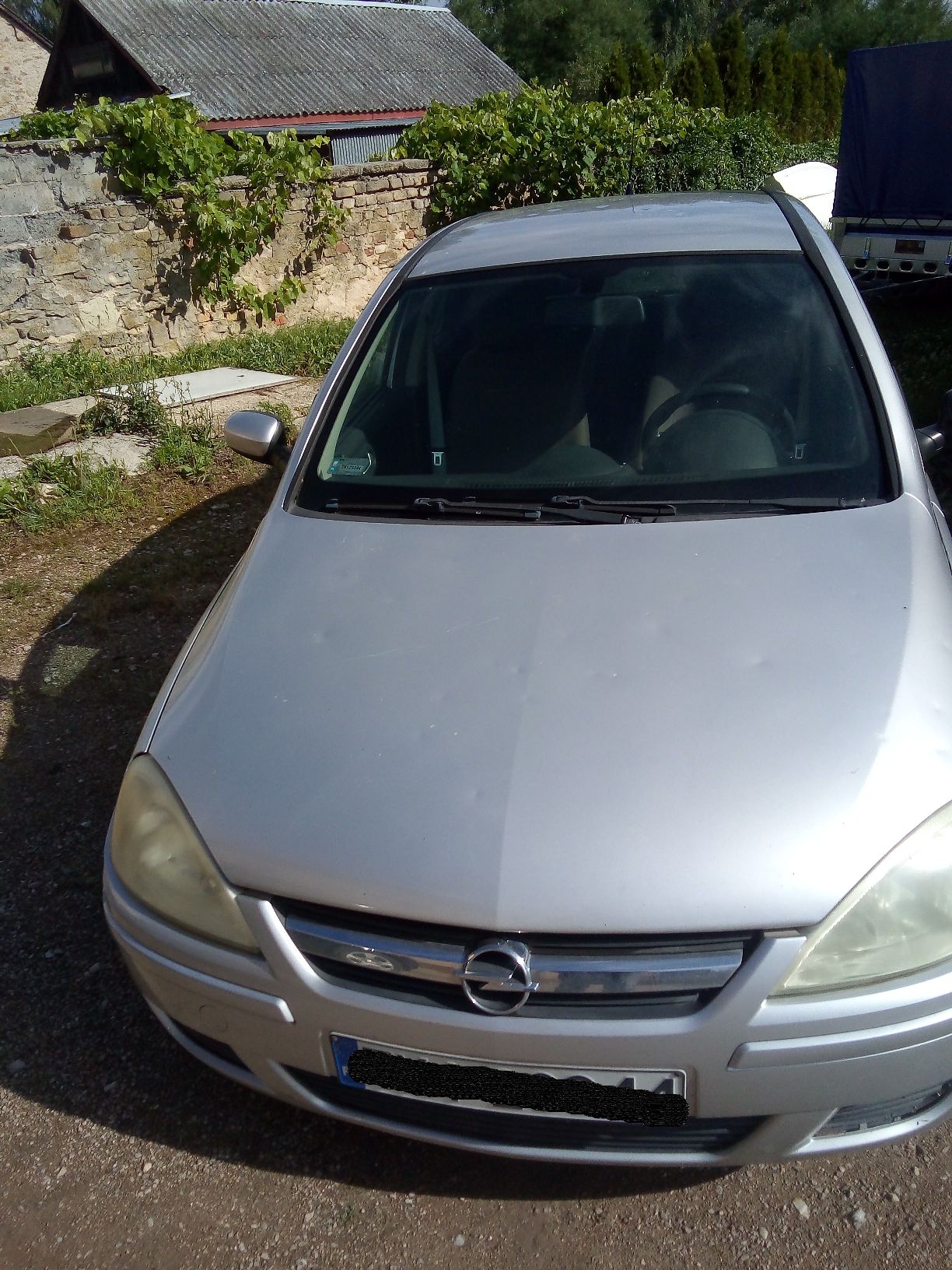 Srebrny samochód osobowy marki Opel widziany z przodu, na karoserii widoczne wgniecenia po gradobiciu