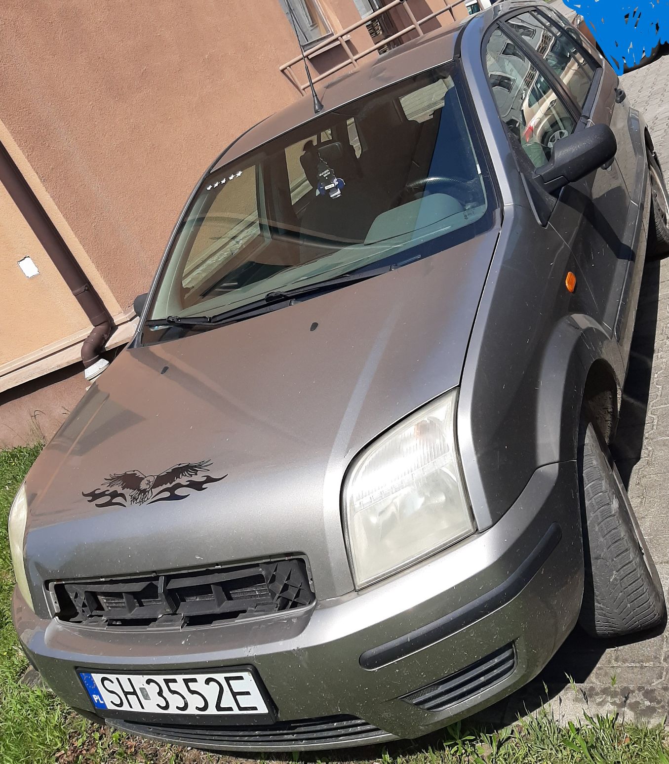 Samochód z przodu od strony kierowcy. Brak atrapy chłodnicy, zmatowiały reflektor, zarysowania na zderzaku.