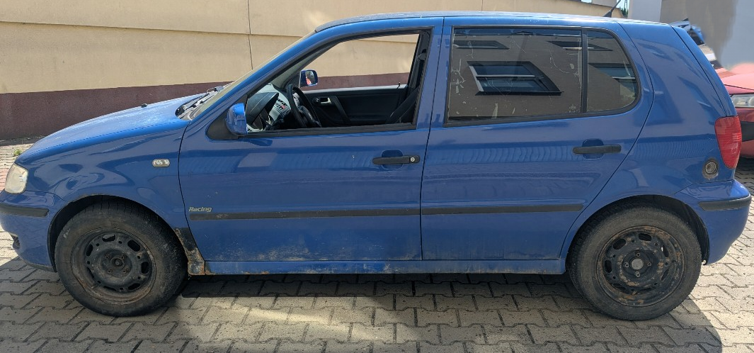 Lewy bok niebieskiego pojazdu VOLKSWAGEN POLO. Na szybie tylnych drzwi założona folia przyciemniająca, wlew gazu z tyłu