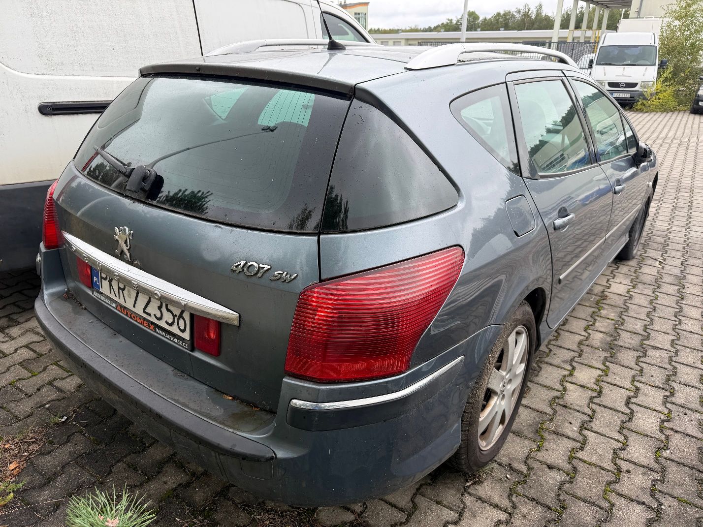 Szary Peugeot 407 SW, widok z tytułu prawego boku, srebrne relingi dachowe oraz chromowana listwa na klapie bagażnika.