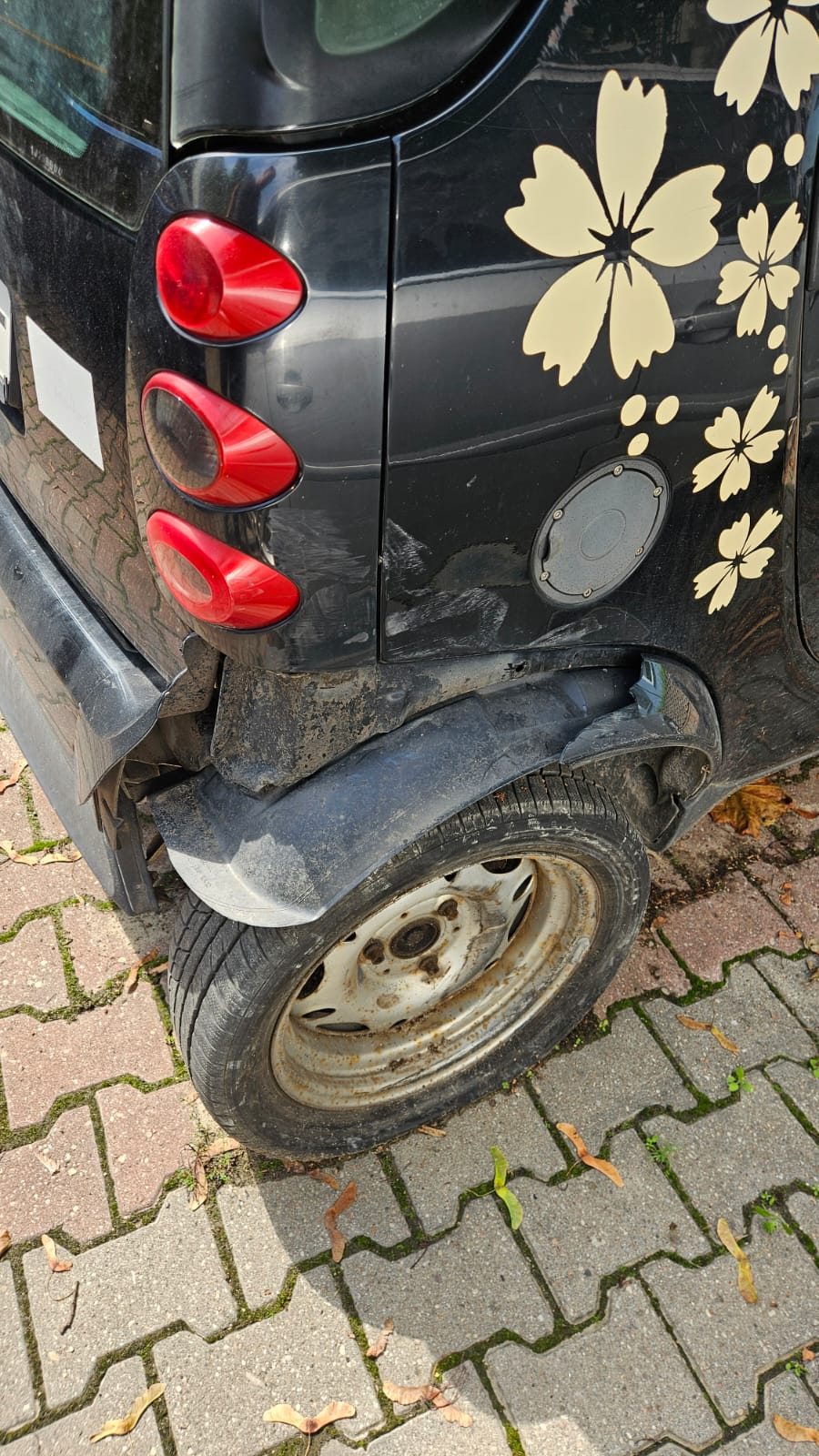 Na zdjęciu widoczny samochód Smart z uszkodzonym tylnym prawym kołem