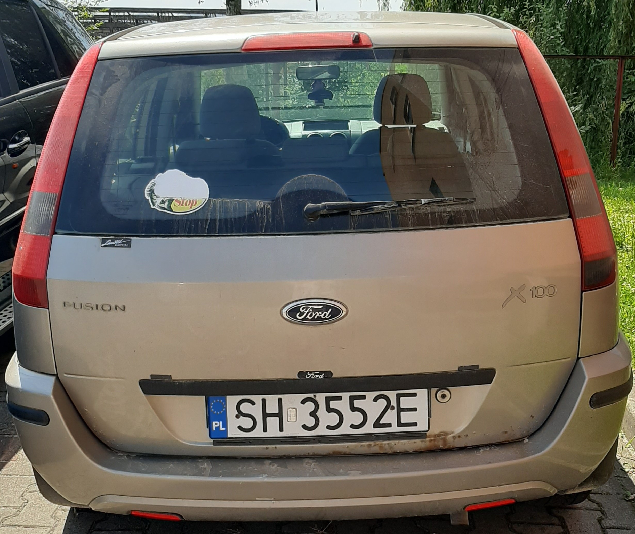 Samochód z tyłu. Korozja pod tablicą rejestracyjną, naklejka na szybie, brak tylnej wycieraczki.