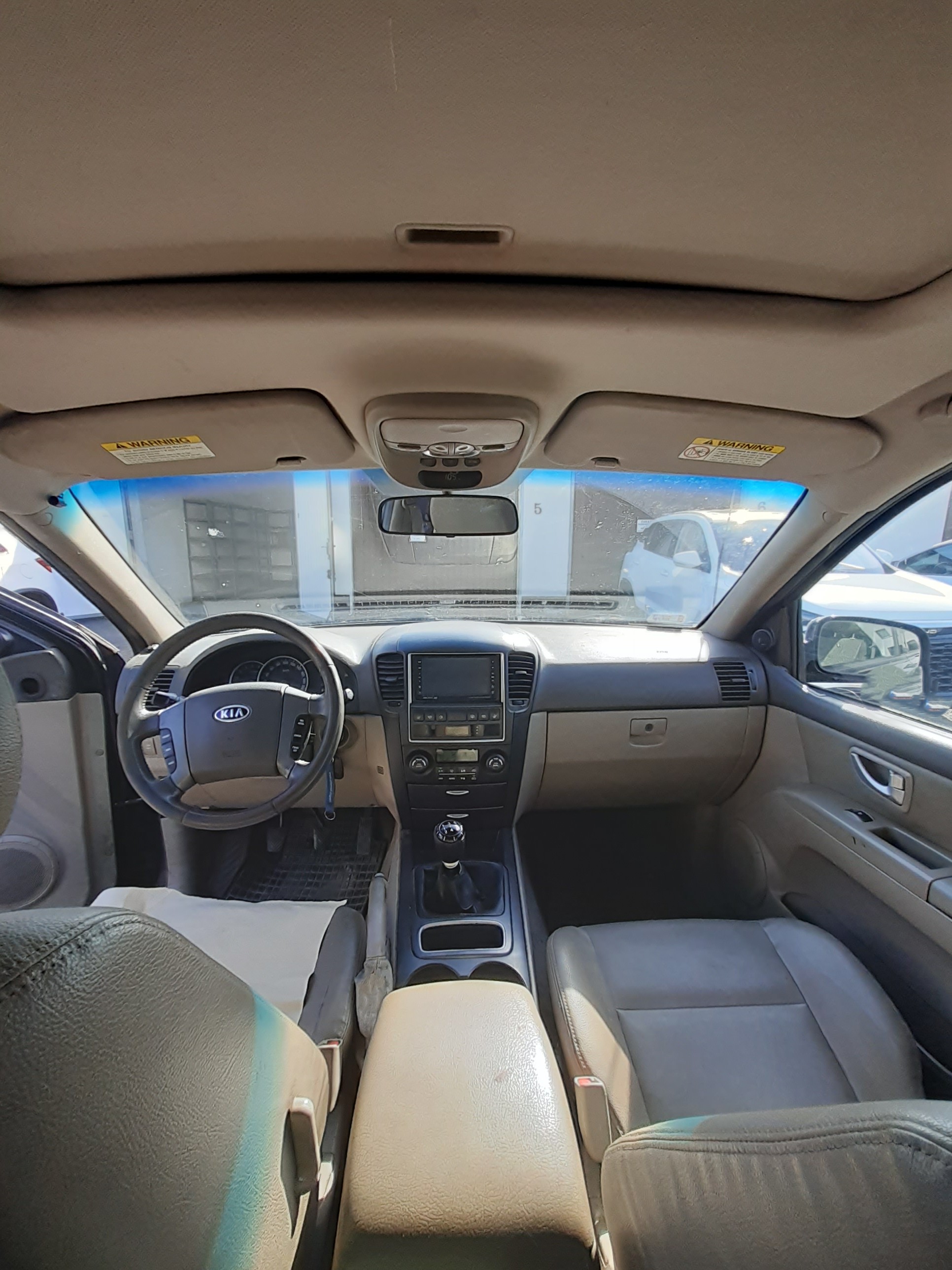 Wnętrze Kia Sorento z jasną skórzaną tapicerką, widoczna kierownicą po lewej stronie i konsola środkowa z radiem.