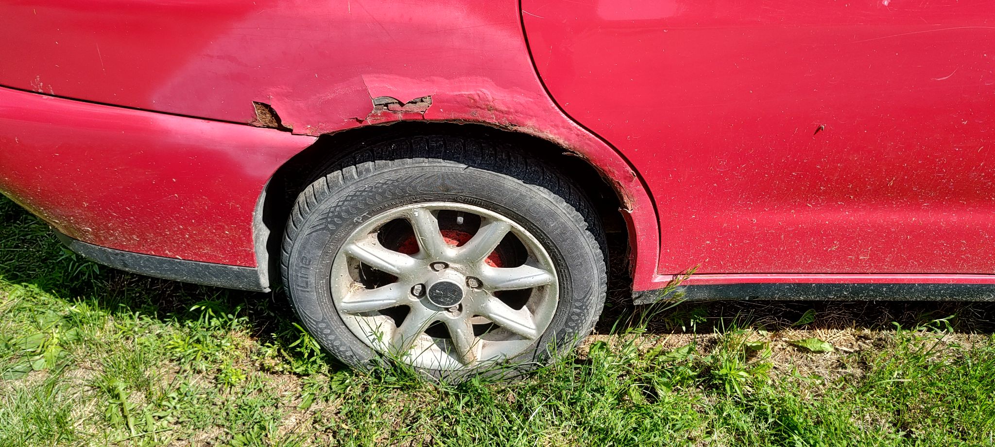 Tylne koło pojazdu po prawej stronie wraz z widocznymi śladami korozji na blacharce nad nadkolem.