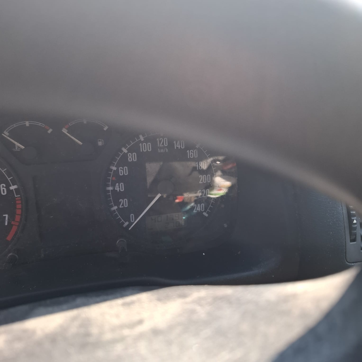 Tablica rozdzielcza samochodu z prędkościomierzem wskazującym 0 km/h, wskaźnikami paliwa i temperatury.