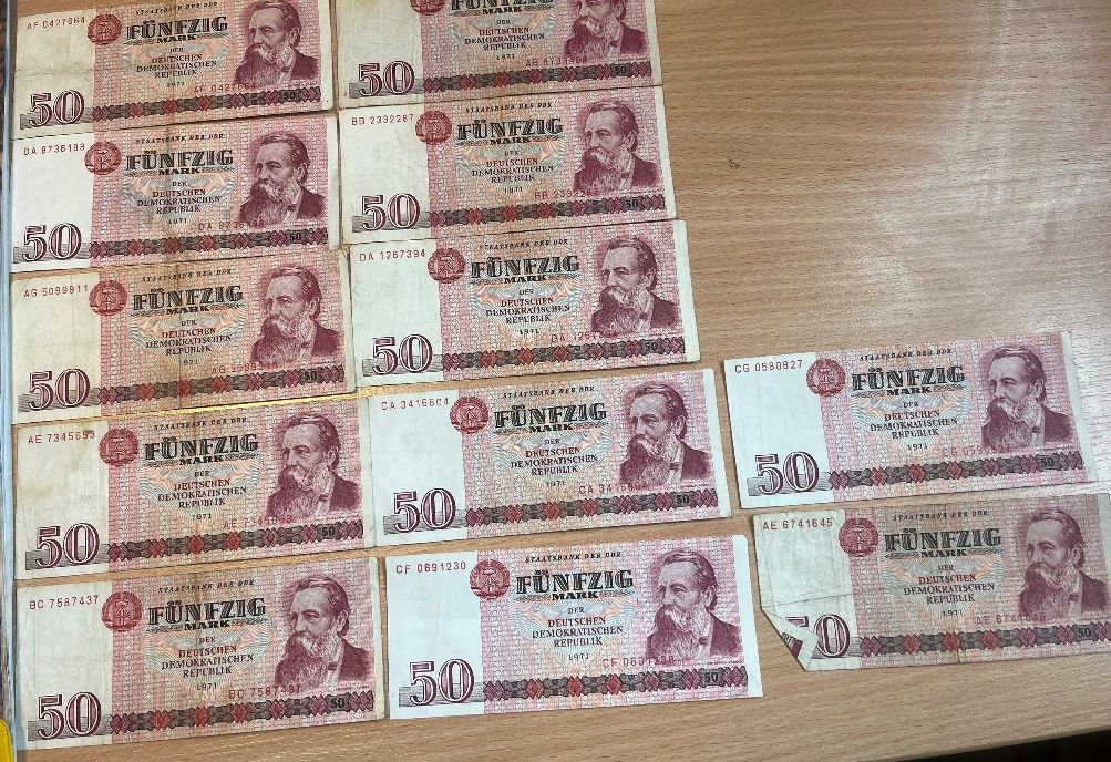 Zestaw banknotów o nominale 50 marek NRD z 1971 roku ułożonych w luźniejszą kompozycję.