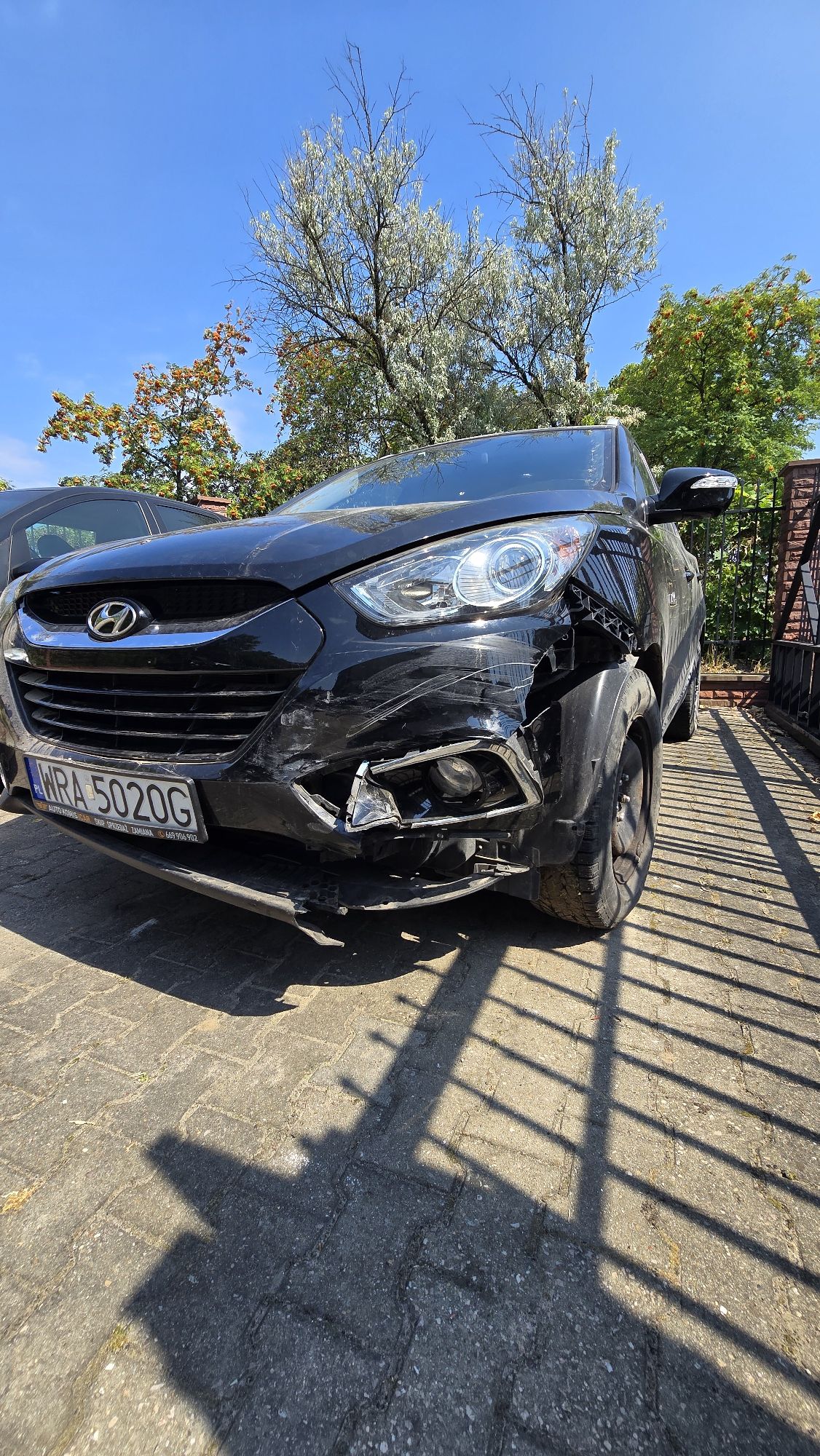 Lewy przód pojazdu. Uszkodzenia zderzaka, uszkodzona dolne światło, zarysowania pod lampami, wiszące plastiki