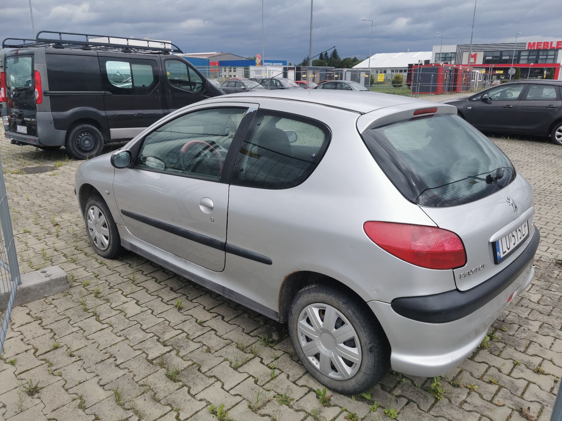 Lewy bok pojazdu. Rdza na tylnym błotniku oraz progu. Koła stalowe z plastikowymi deklami. Drzwi bez uszkodzeń.