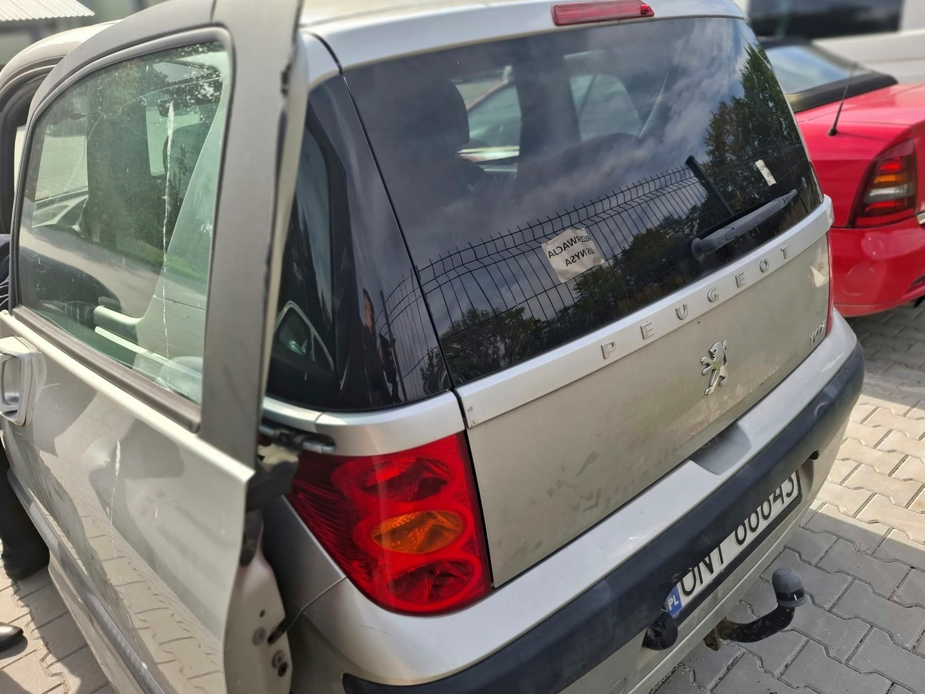 zdjęcie tyłu srebrnego samochodu osobowego Peugeot 1007 wraz z otwartymi drzwiami przesuwnymi.