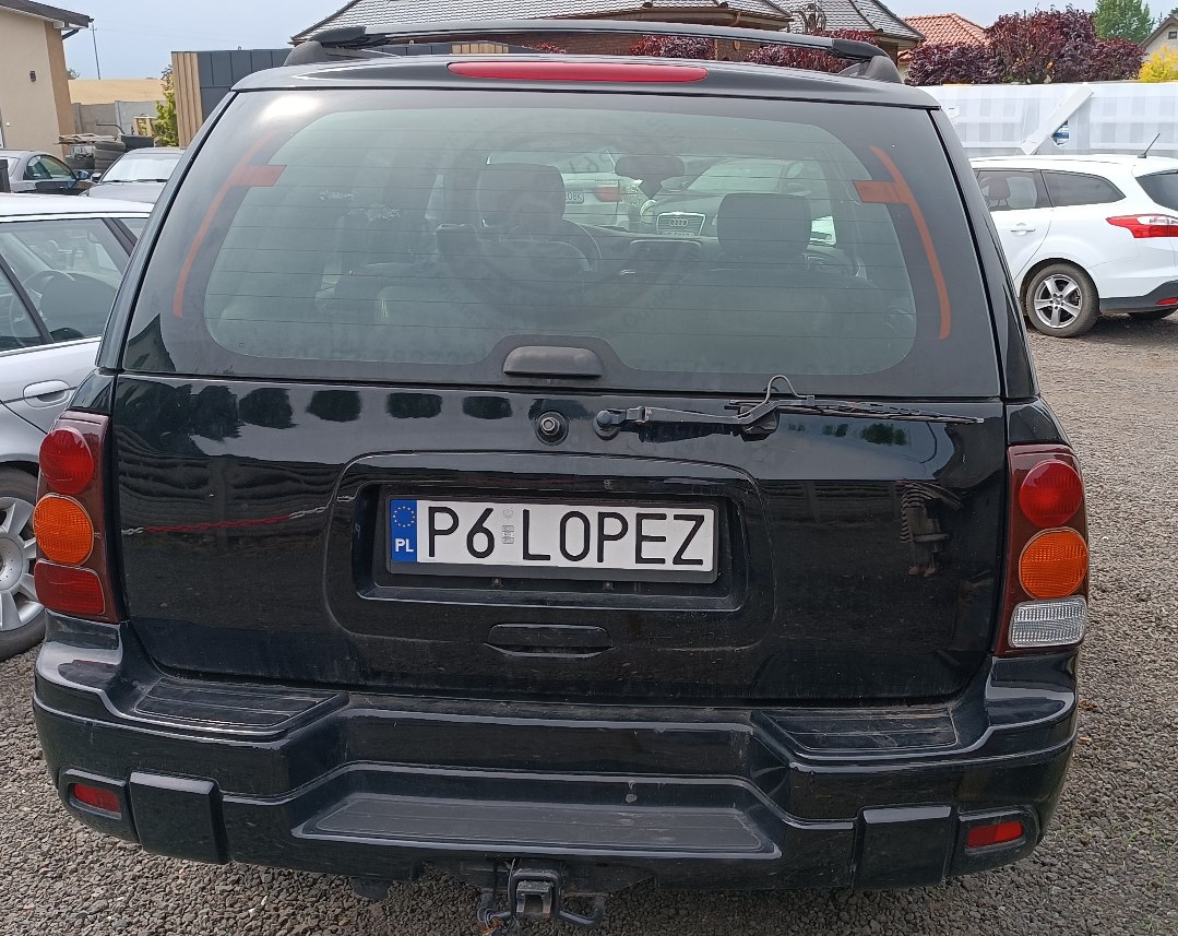 Polska tablica rejestracyjna o numerze P6 LOPEZ, nad tablicą znajduje się klamka do otwierania szyby lub klapy oraz zamek.