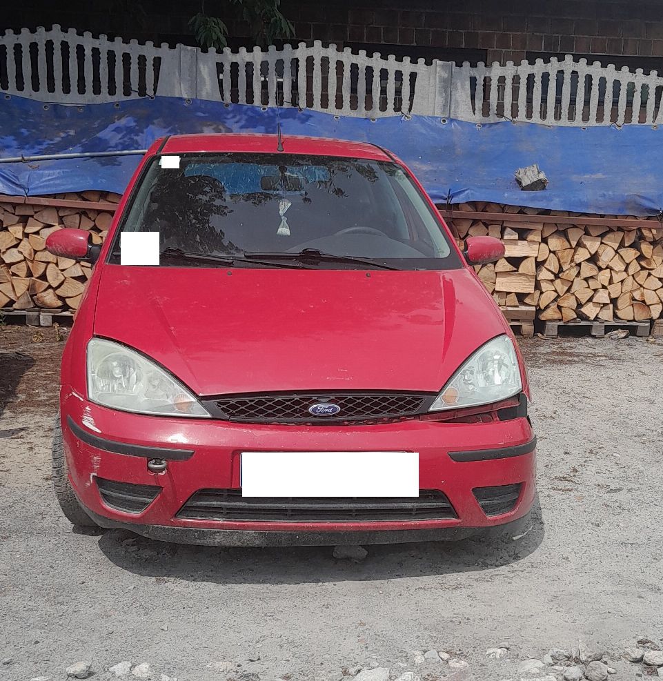 Czerwony Ford Focus, widziany od przodu pojazdu z uszkodzonym zderzakiem
