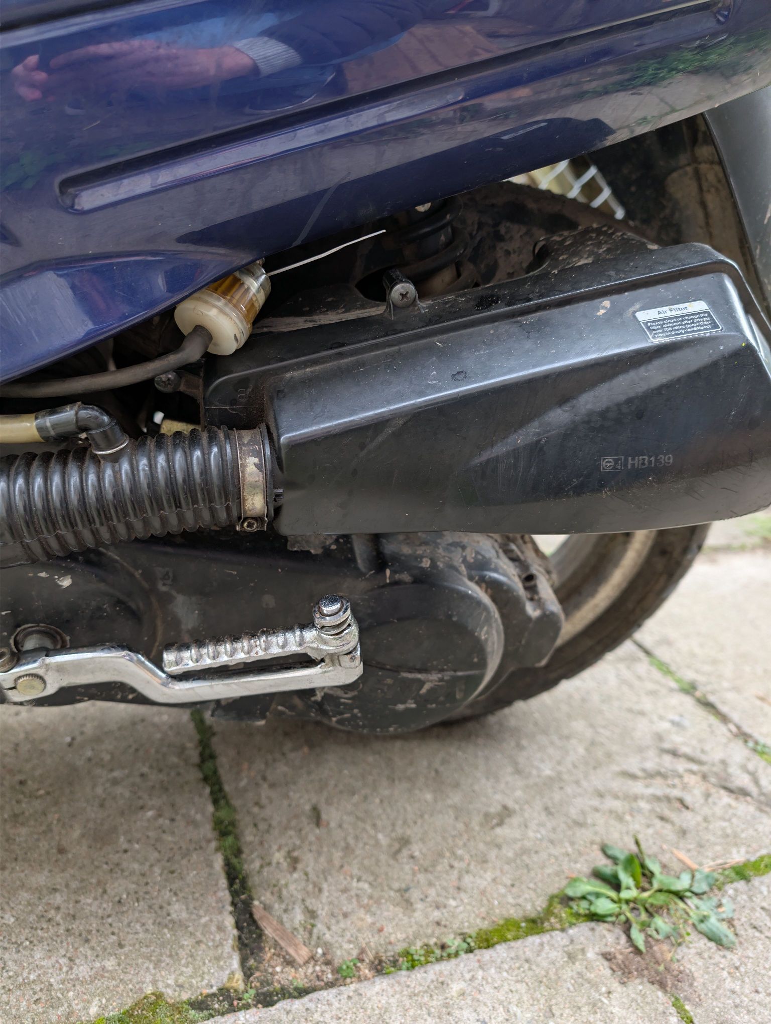 Na zdjęciu widać tylną, lewą część motoroweru. Elementy są zabrudzone i mają ślady normalnej eksploatacji.