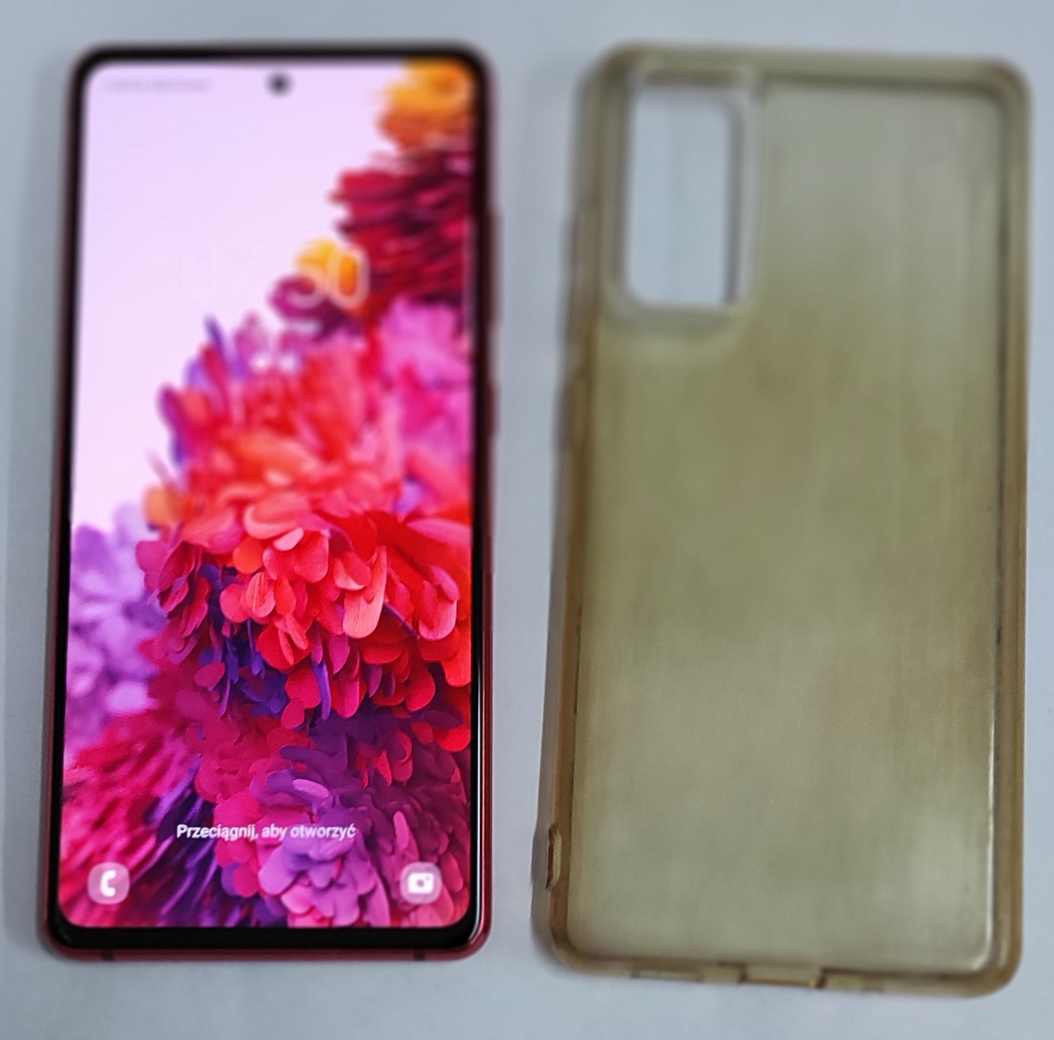 Włączony telefon ze stroną startową, obok przeźroczyste etui