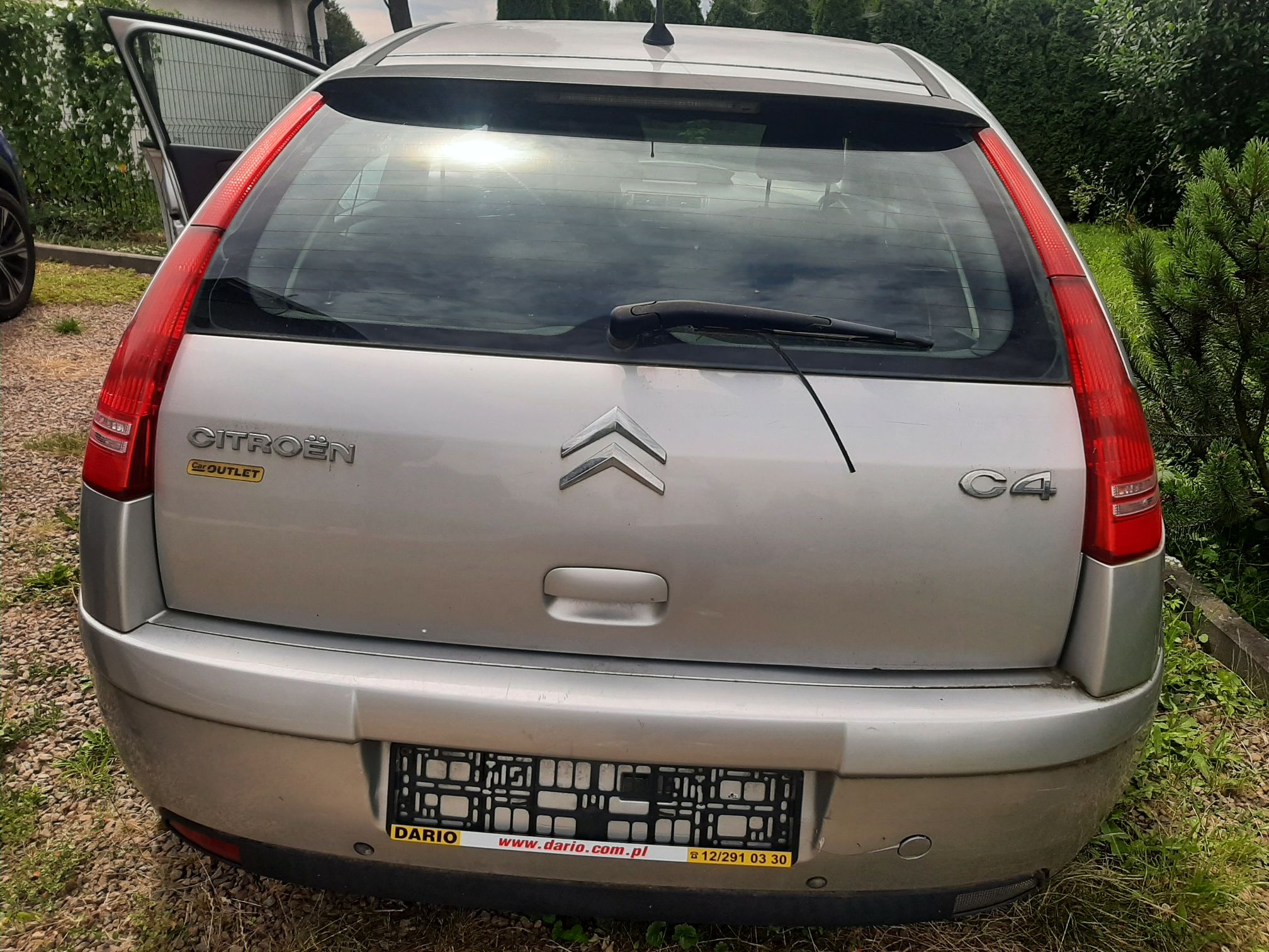 Srebrny Citroen C4 od tyłu. Widoczna klapa bagażnika z logo, pionowe lampy, wycieraczka i ramka tablicy rejestracyjnej.