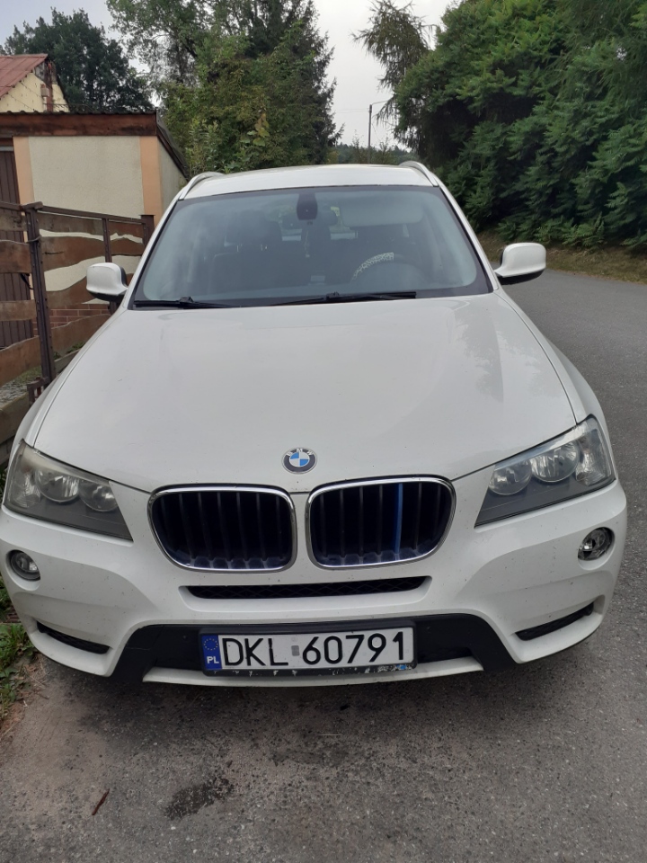 Biały samochód marki BMW X z polskimi tablicami rejestracyjnymi DKL 60791, widok z przodu