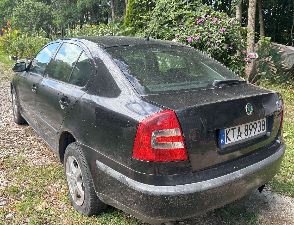 Tył czarnej Skody Octavii II pokazujący stan karoserii, tylną szybę z wycieraczką oraz lewy bok pojazdu z aluminiowymi felgami.