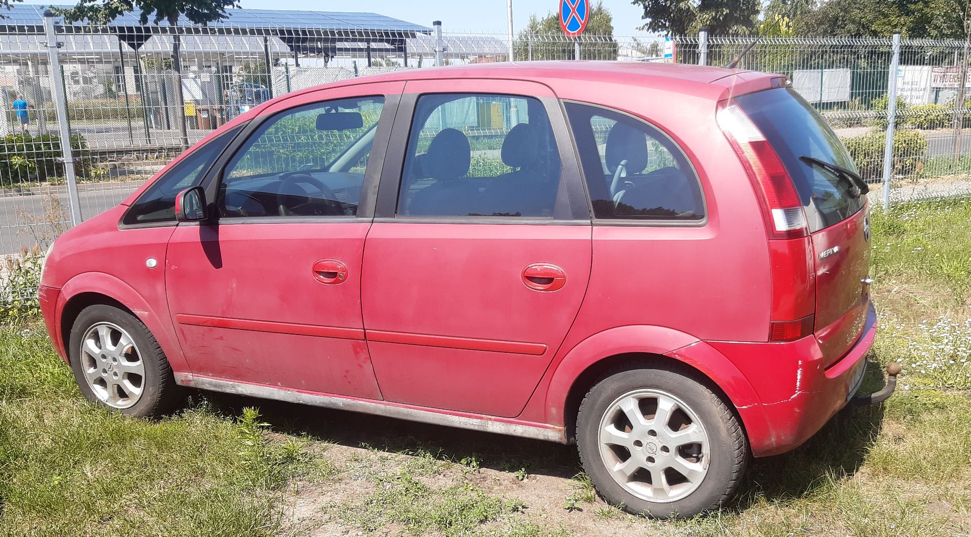 Czerwony minivan widziany z boku, z widocznymi otarciami oraz zarysowaniami