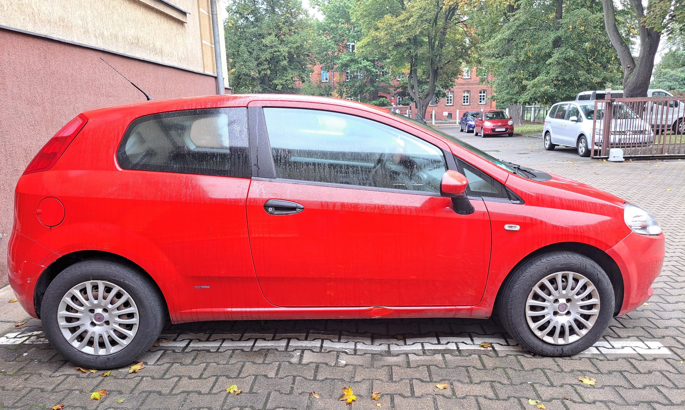 prawa strona czerwonego samochodu osobowego Fiata Punto lekkie wgniecenie na progu drobne zarysowania na tylnym zderzaku