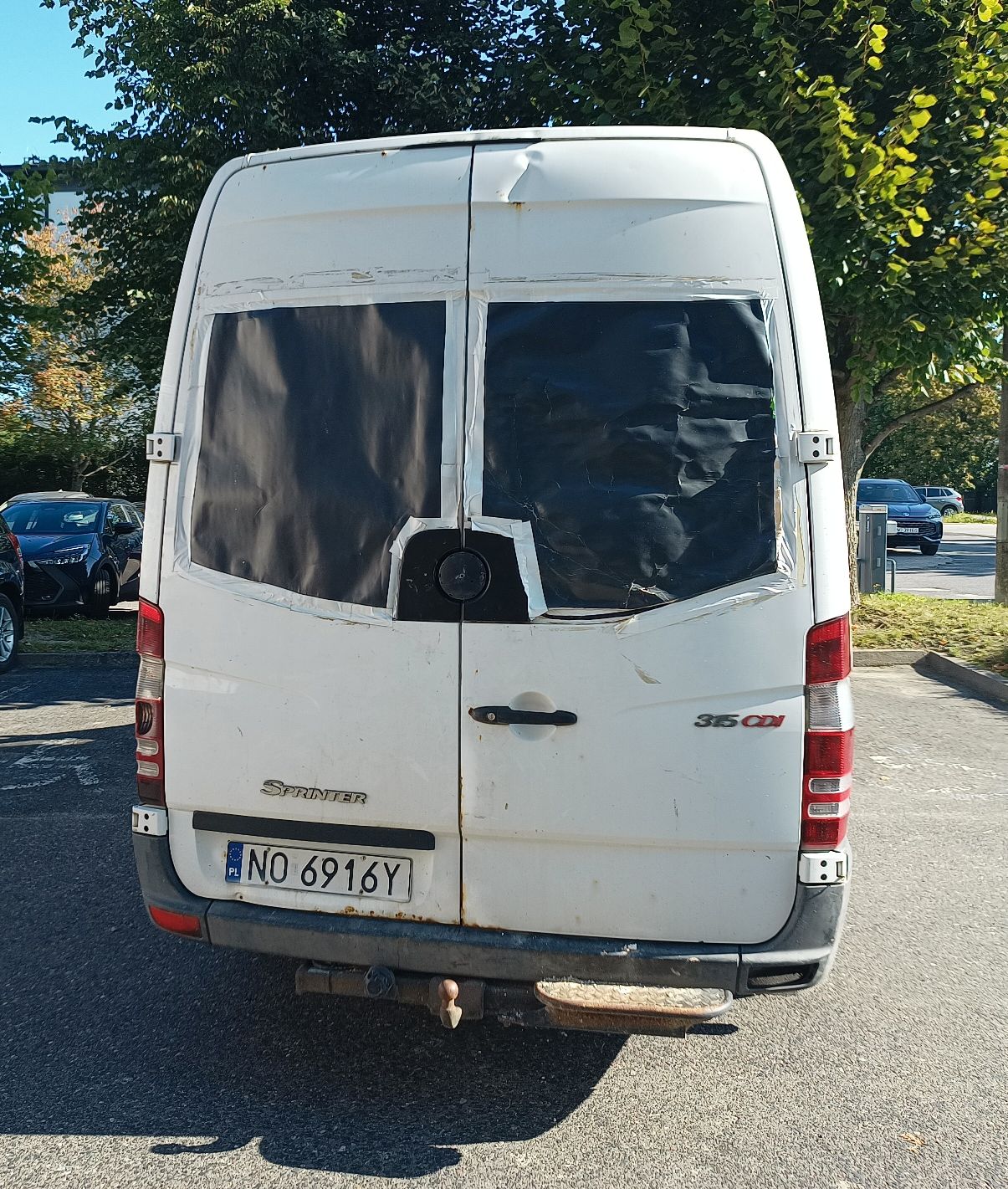 Na zdjęciu znajduje się tył samochodu. Widoczna jest czarna tektura zamiast tylnych szyb, widoczna duże ogniska korozji.