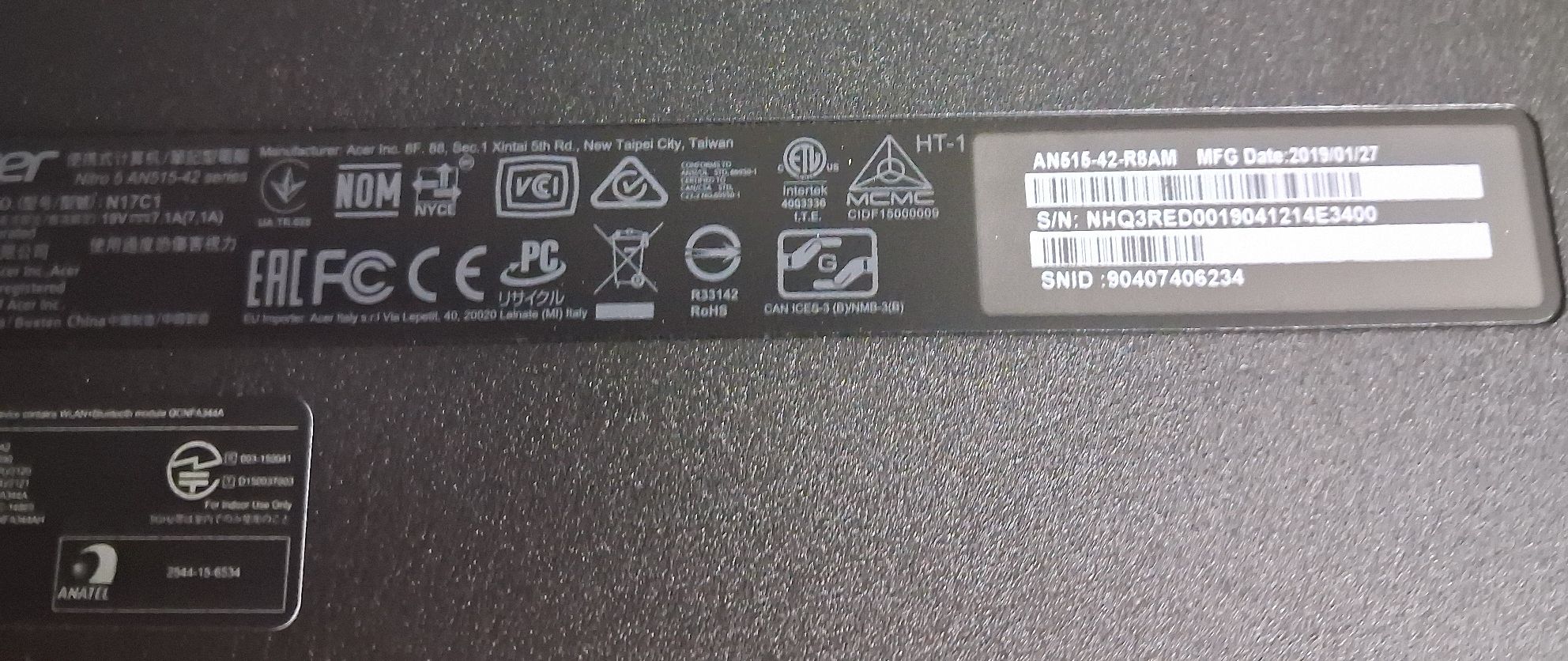 Spodnia część laptopa z widoczną naklejką znamionową.