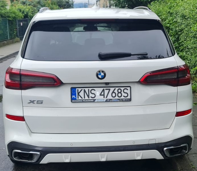 Tylna część białego samochodu marki BMW X5 z polskimi tablicami rejestracyjnymi.