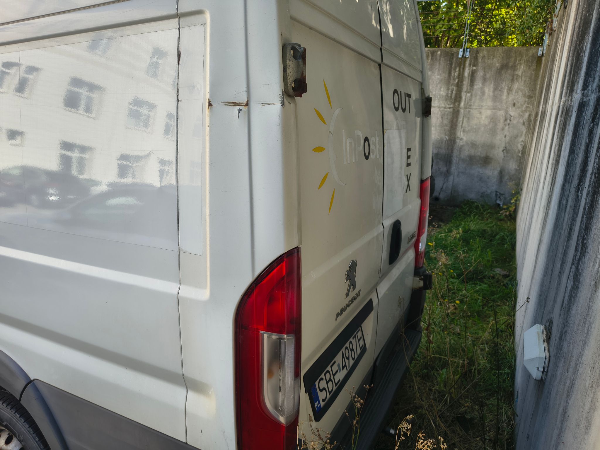 Lewy, tylny róg pojazdu, widoczne zarysowanie na górnej krawędzi pojazdu. Widoczna lewa tylna lampa.