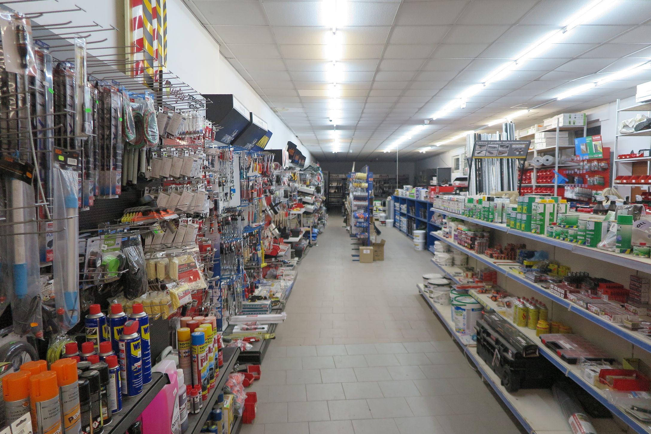 Pomieszczenie sklepu, zagospodarowane regałami z materiałami budowlanymi.