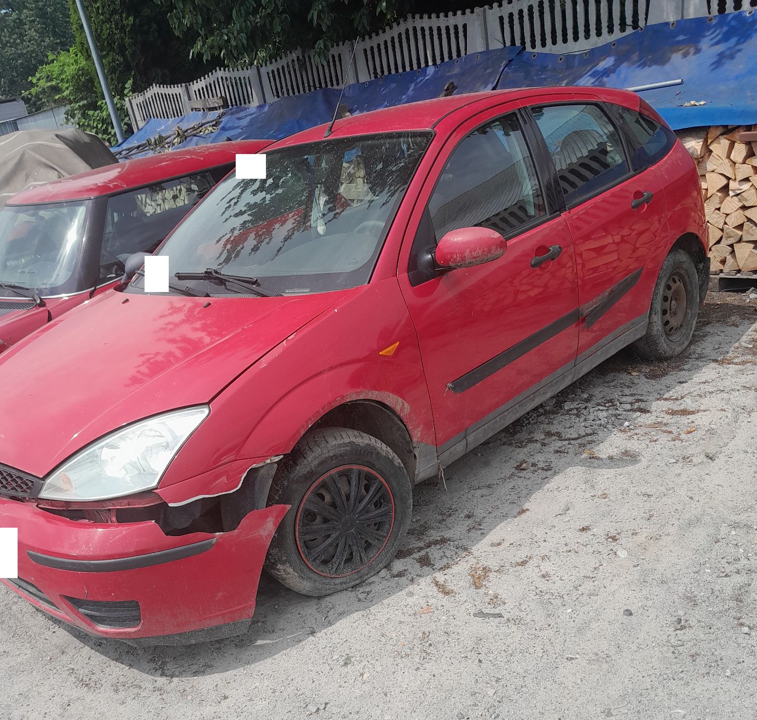 Czerwony Ford Focus, widziany od lewej strony z oberwanym zderzakiem