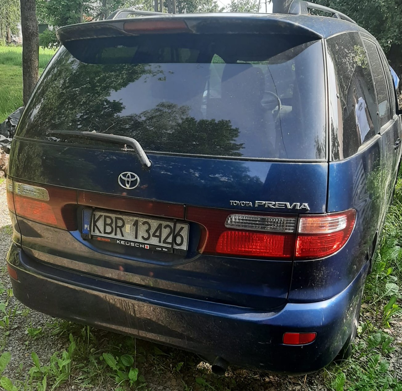 Tył samochodu Toyota Previa wraz z tablicą rejestracyjną KBR 13426. Kolor pojazdu granatowy.