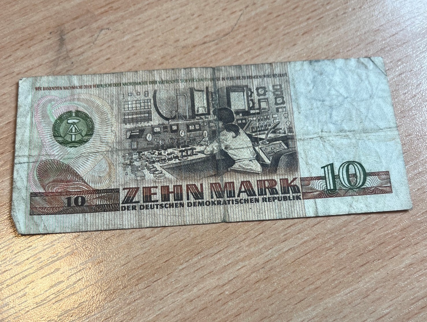 Odwrotna strona obiegowego banknotu 10 marek NRD z widocznymi zagnieceniami.