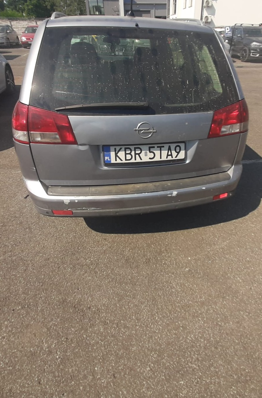 Tył samochodu Opel Vectra, kolor srebrny. Widoczne uszkodzenia karoserii, tj. obicia i wgniecenia.
