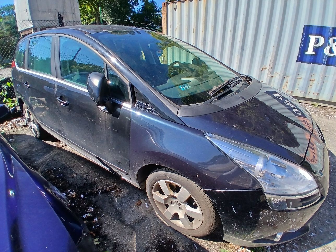 Prawy bok czarnego Peugeota 5008 z widocznym brakiem elementu maskującego przy słupku A