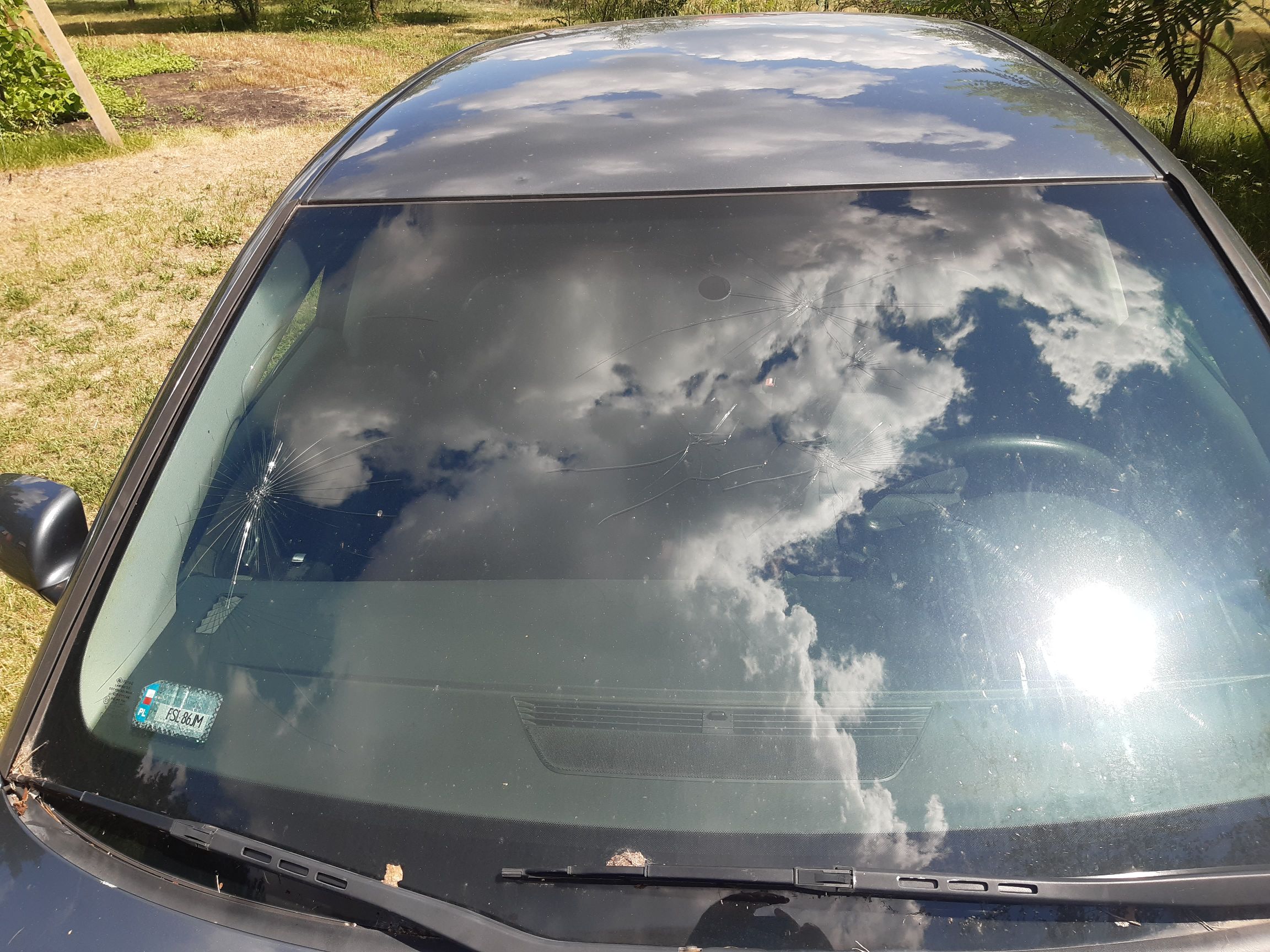 Widok z góry na popękaną przednią szybę szarego auta Audi A4.