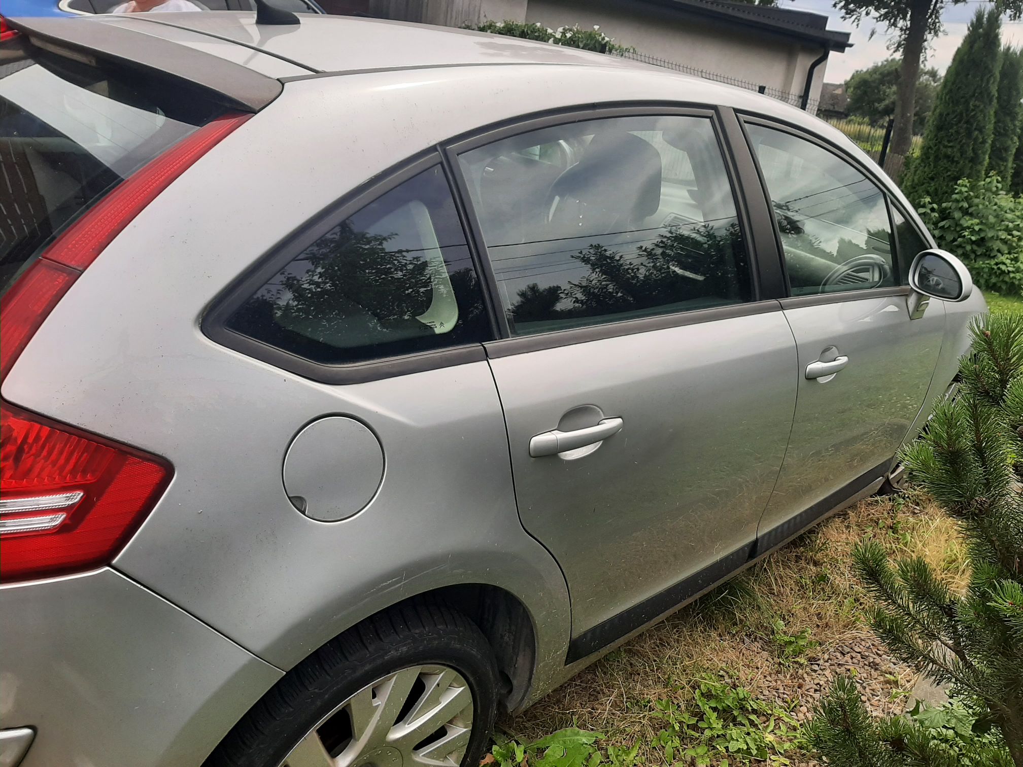 Srebrny Citroen C4 z boku. Widoczne zarysowania na błotniku nad tylnym kołem.