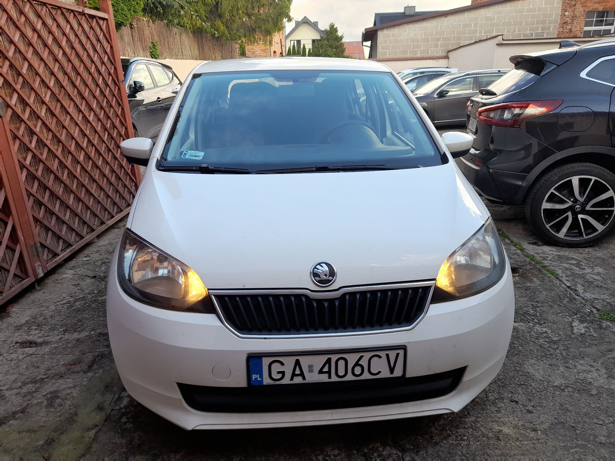 Widok samochodu od przodu, znak firmy Skoda, włączone światła, reflektory bez uszkodzeń