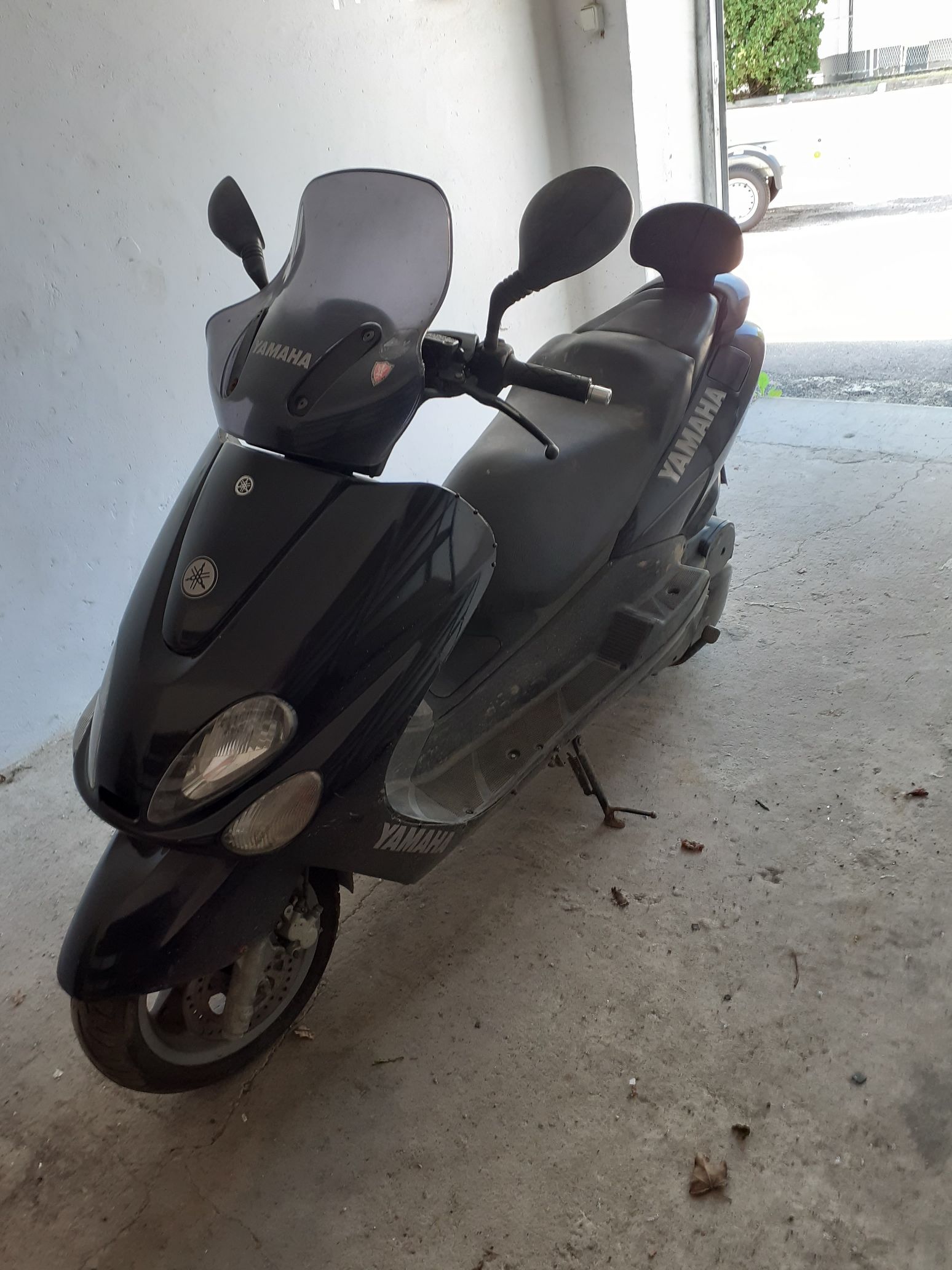 Czarny motorower Yamaha Majesty z przednią szybą i profilowaną kanapą z oparciem.
