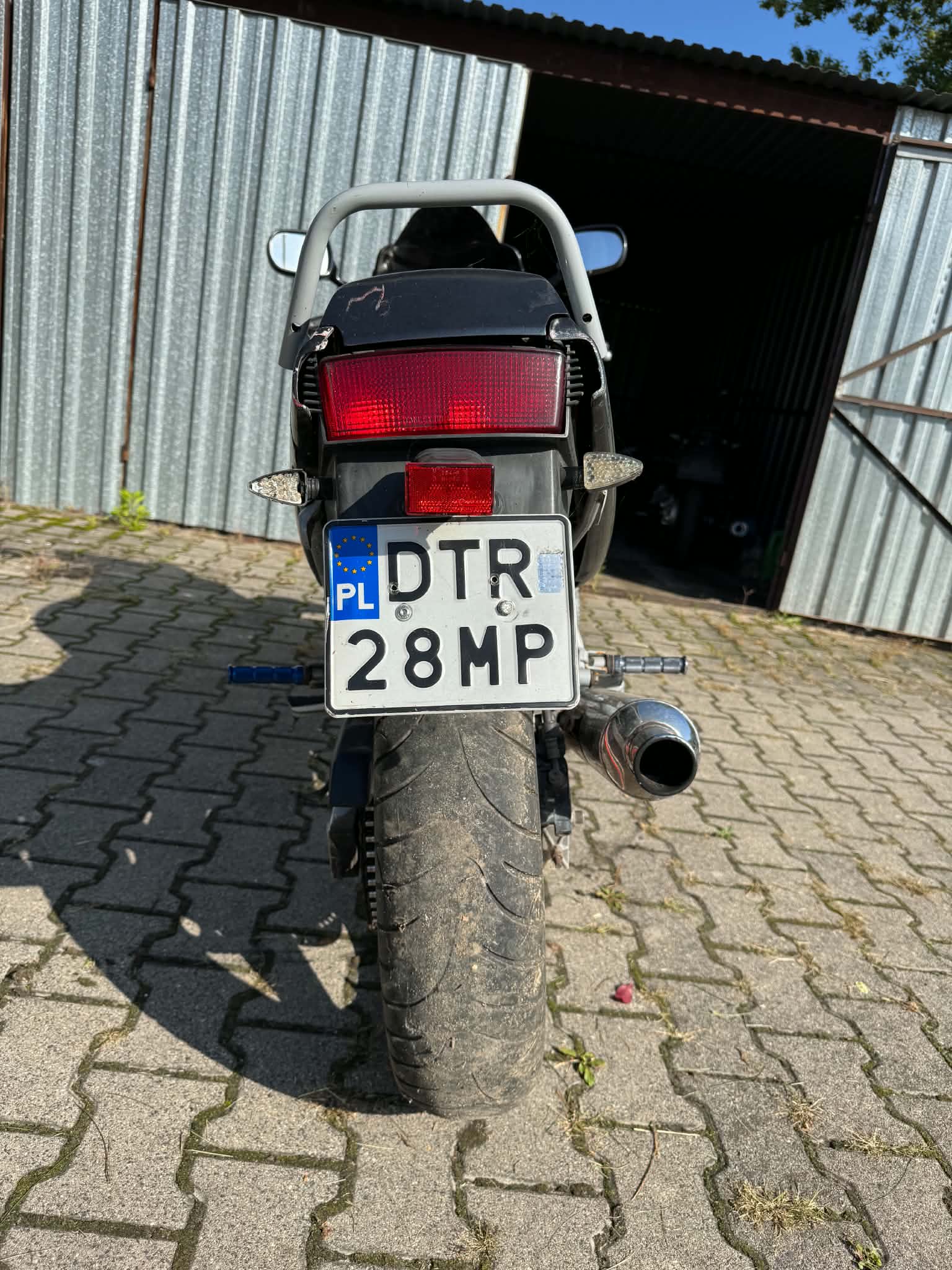 Motocykl widoczny z tyłu, lewy migacz uszkodzony